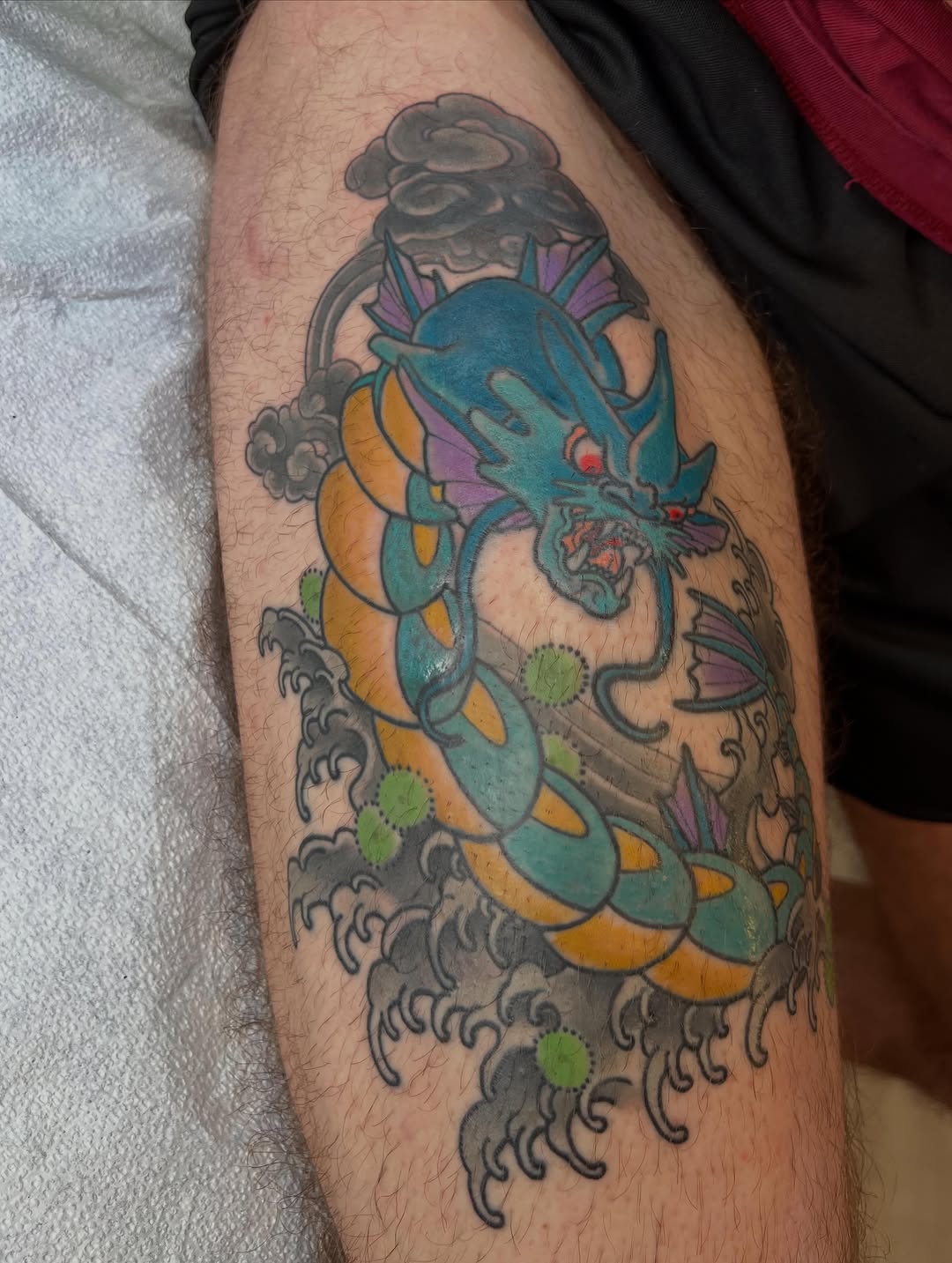 Gyarados dragon with waves American traditional tattoo on the thigh by Troy David Souders