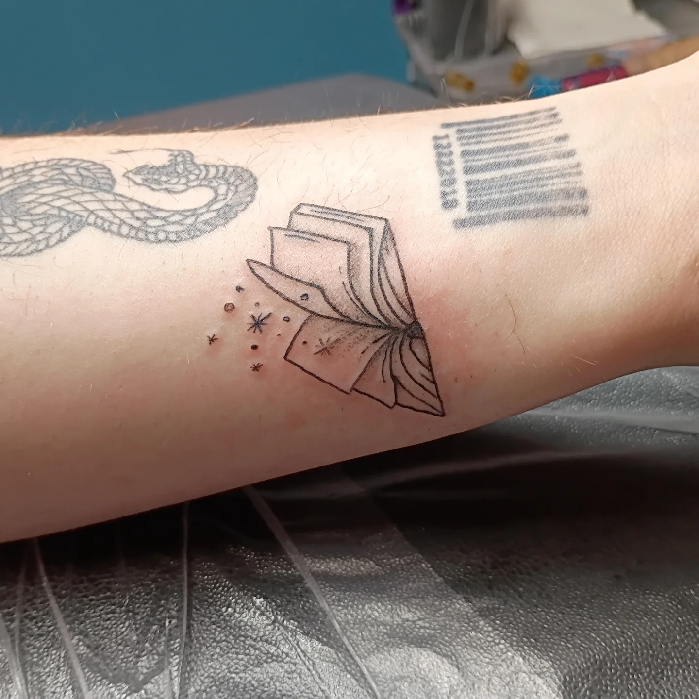 Book and stars black and grey tattoo on the forearm by Tiffany