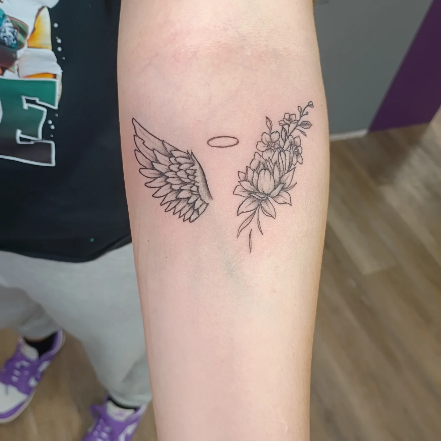 Wings and flowers black and grey tattoo on the forearm by Tiffany