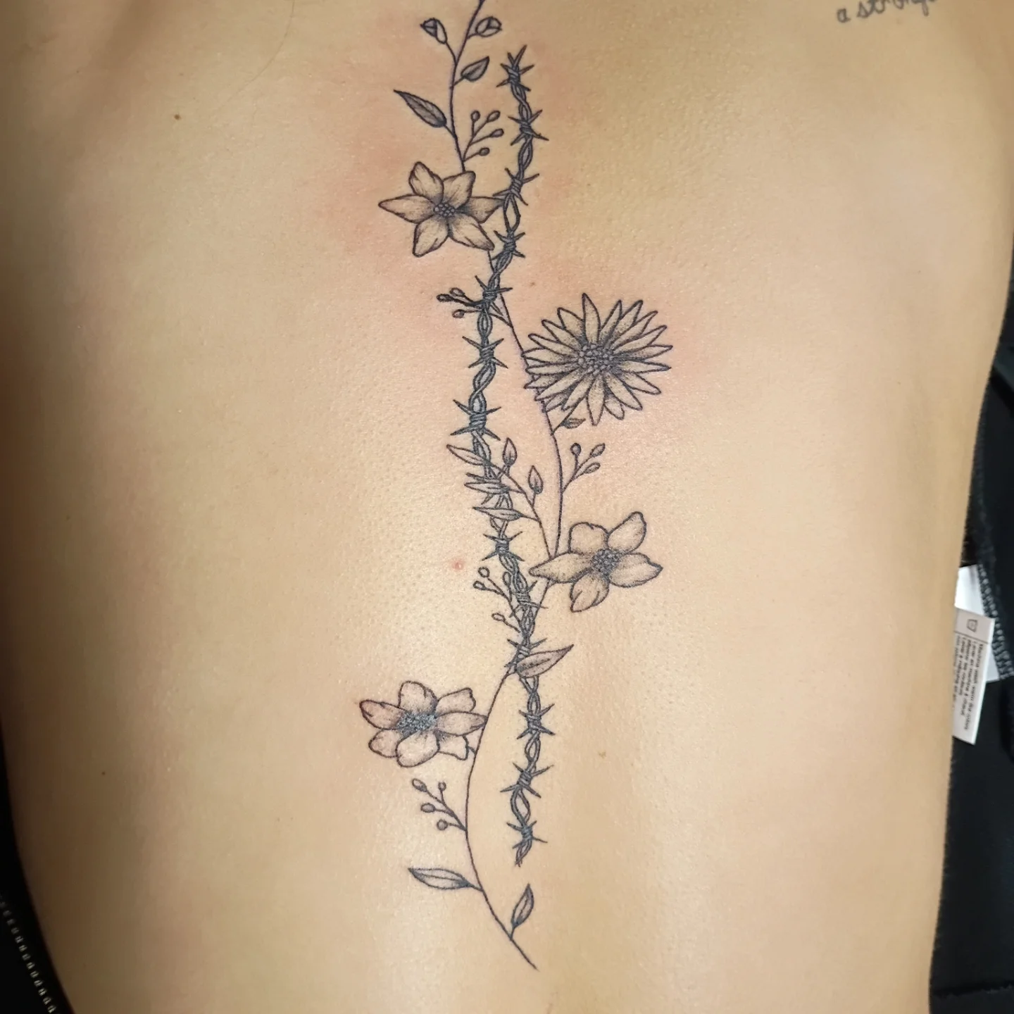 Barbed wire and flowers black and grey tattoo on the ribs by Tiffany
