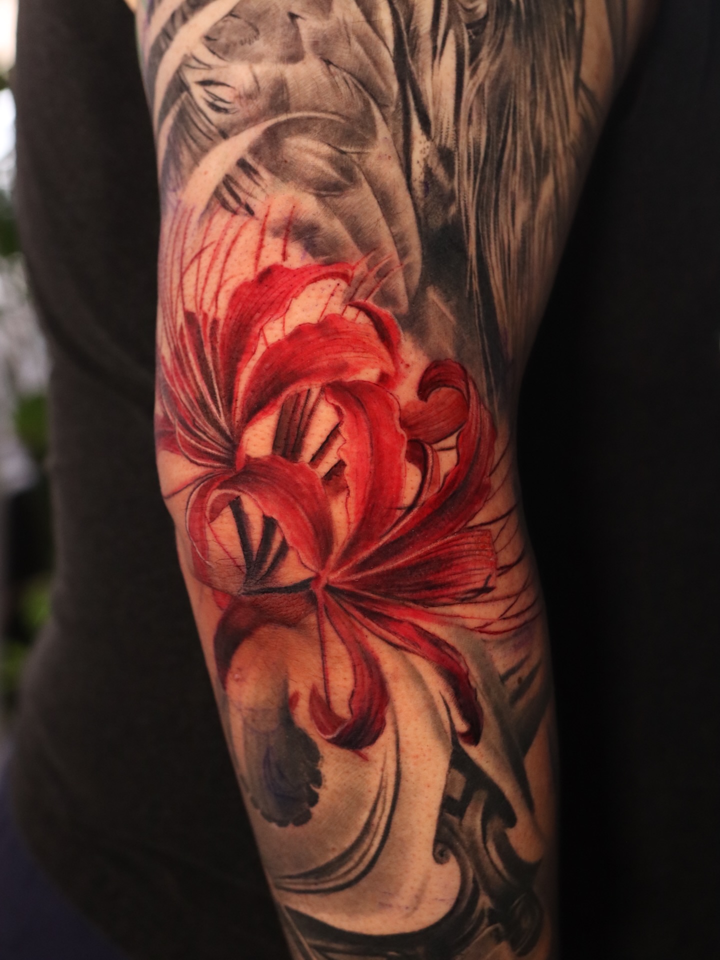 Red lilies realism tattoo on the forearm by Naomi Burke, New Westminster, British Columbia