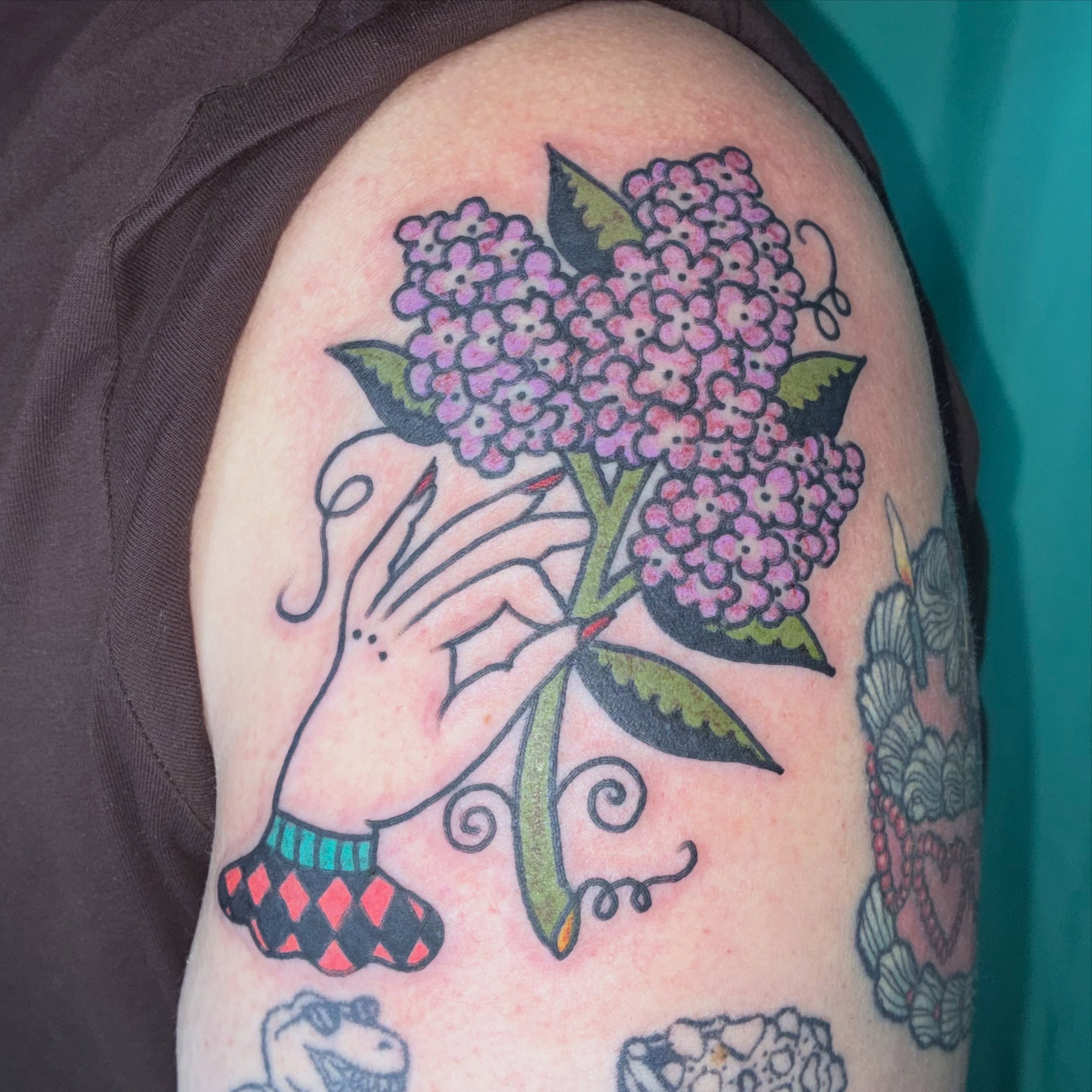 Hand holding flowers American traditional tattoo on the shoulder by Kaily McKee
