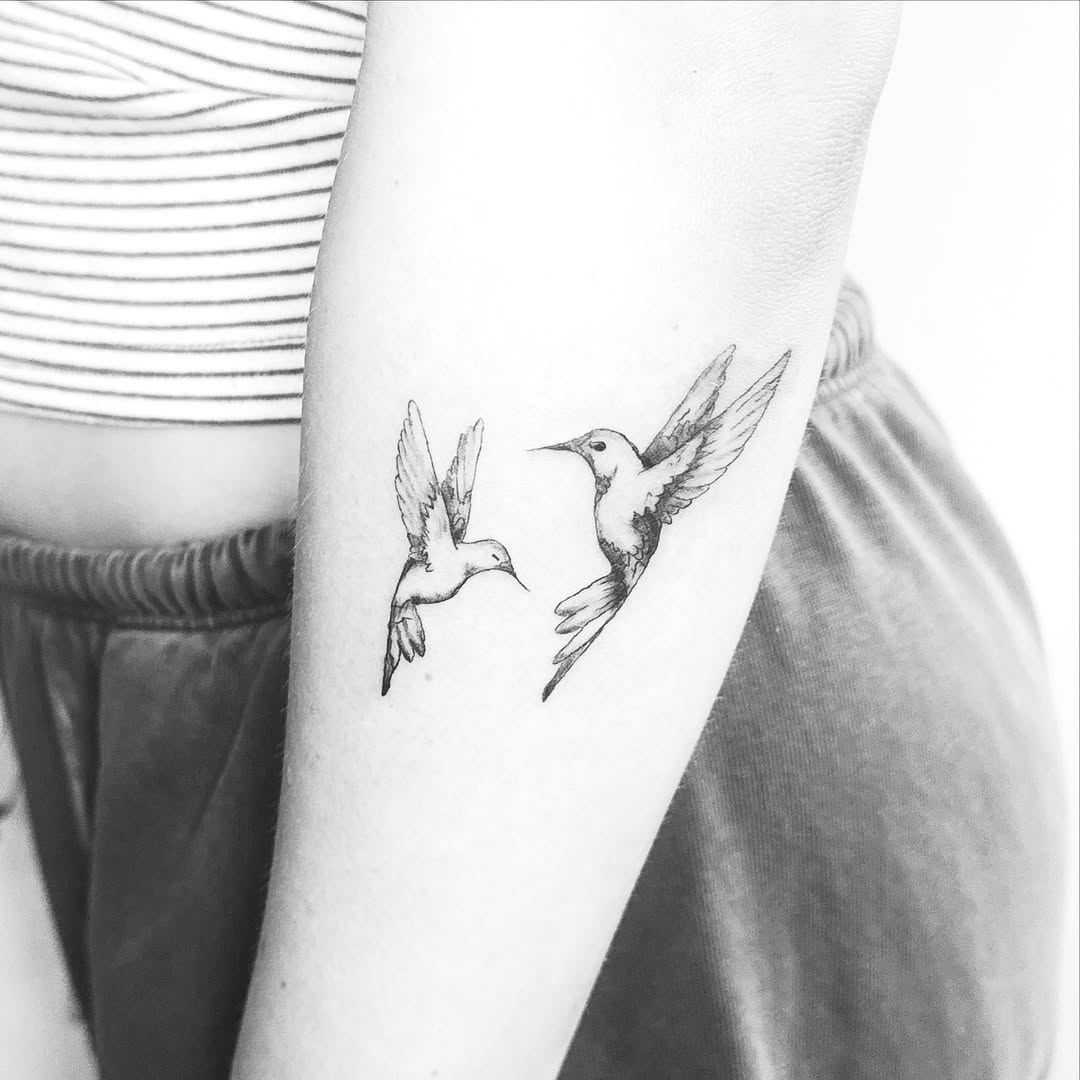 Two hummingbirds fine line tattoo on the forearm by Kylee Snow