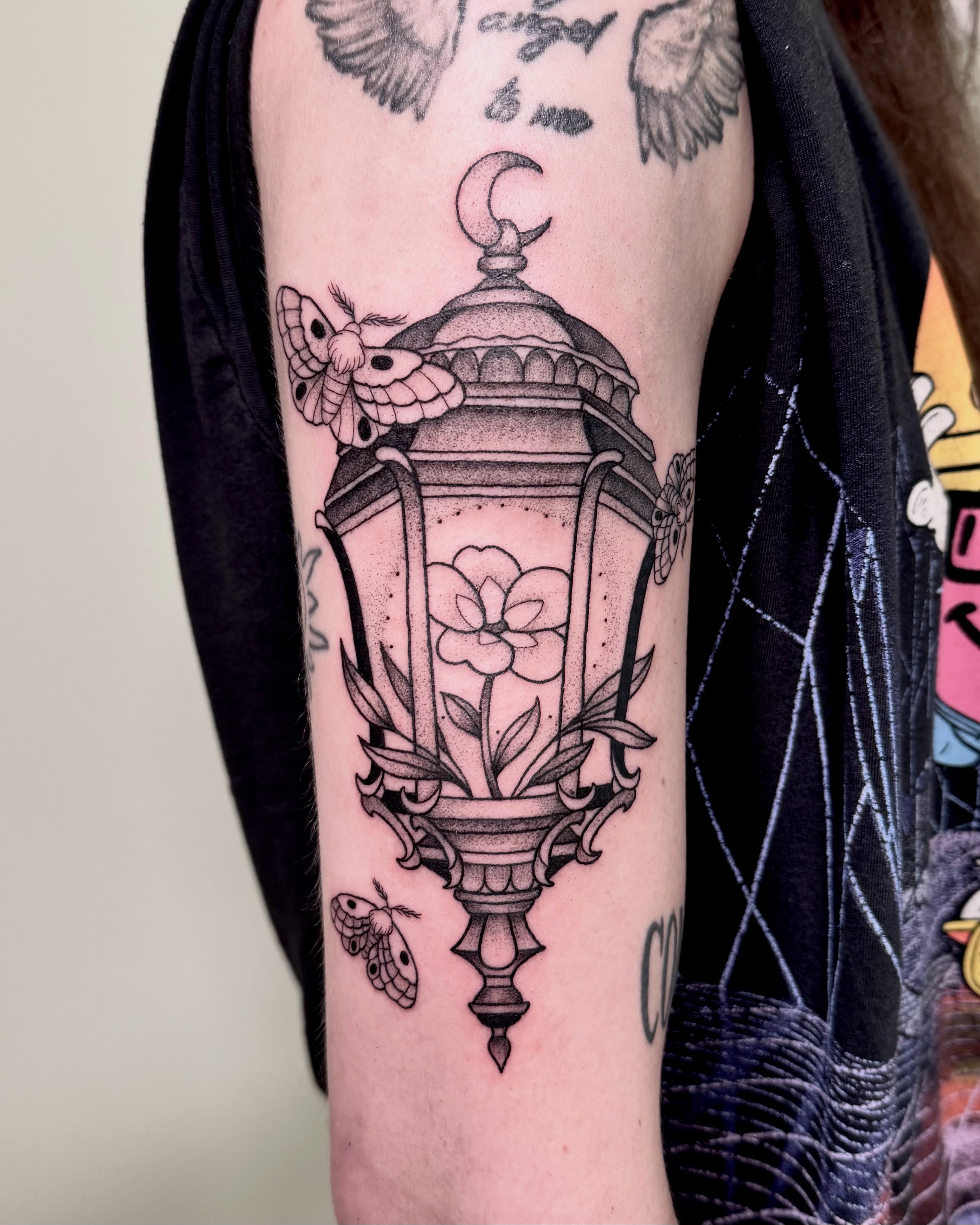Lantern with moth and flower dotwork tattoo on the forearm by Eden Allen