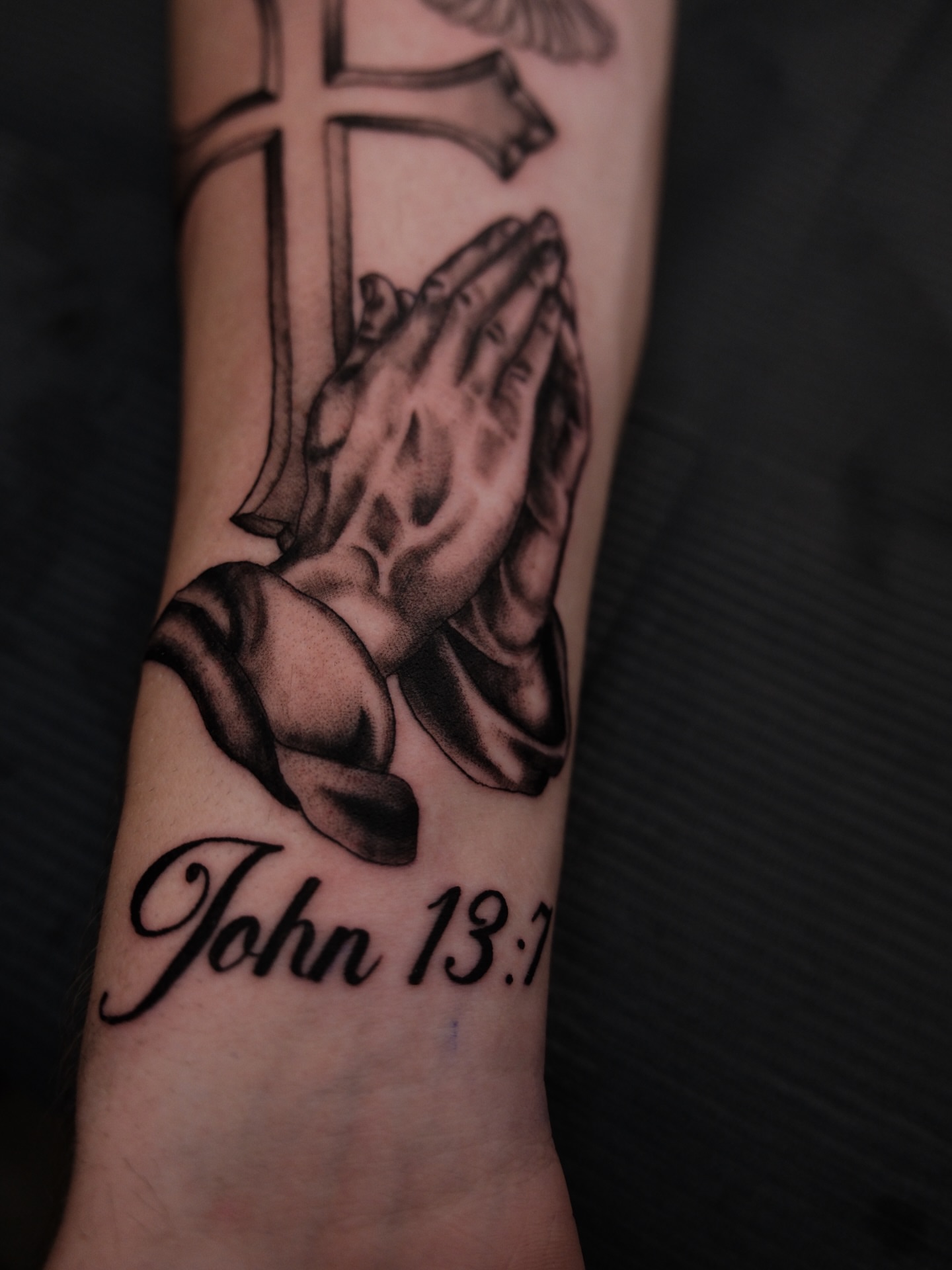 Praying hands black and grey tattoo on the forearm by Kiana Hope