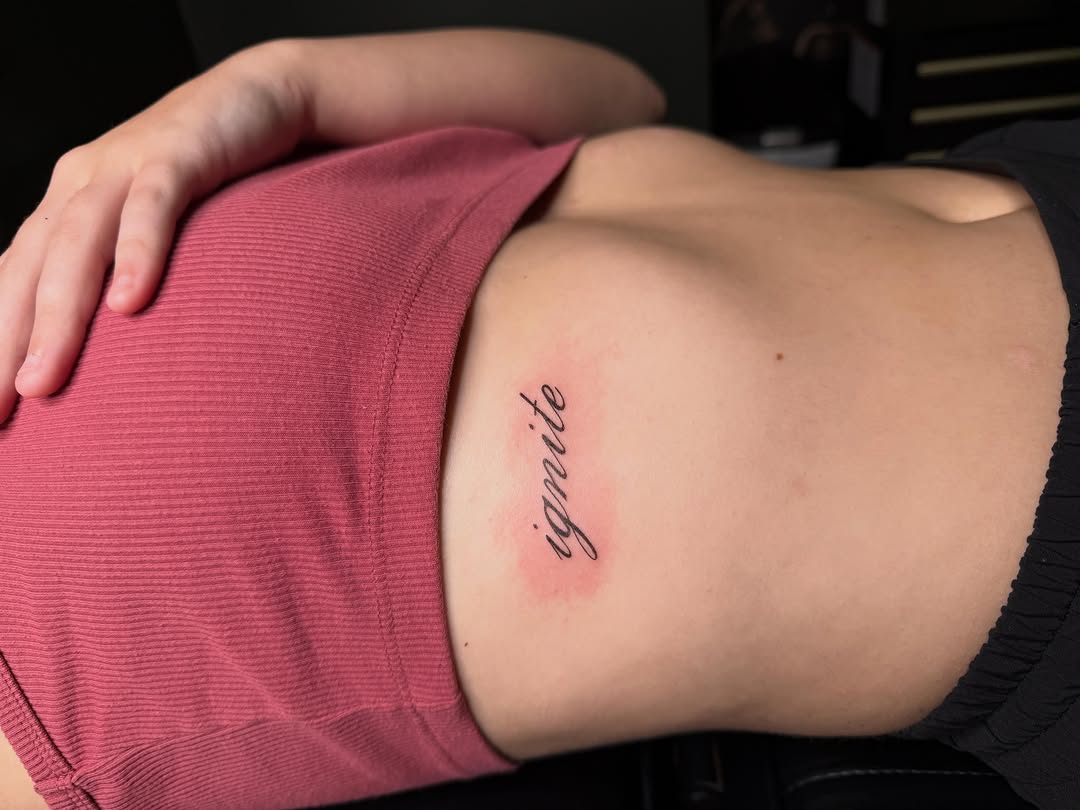 Ignite script lettering tattoo on the torso by Fineline Tattoos π€ Hailey L.