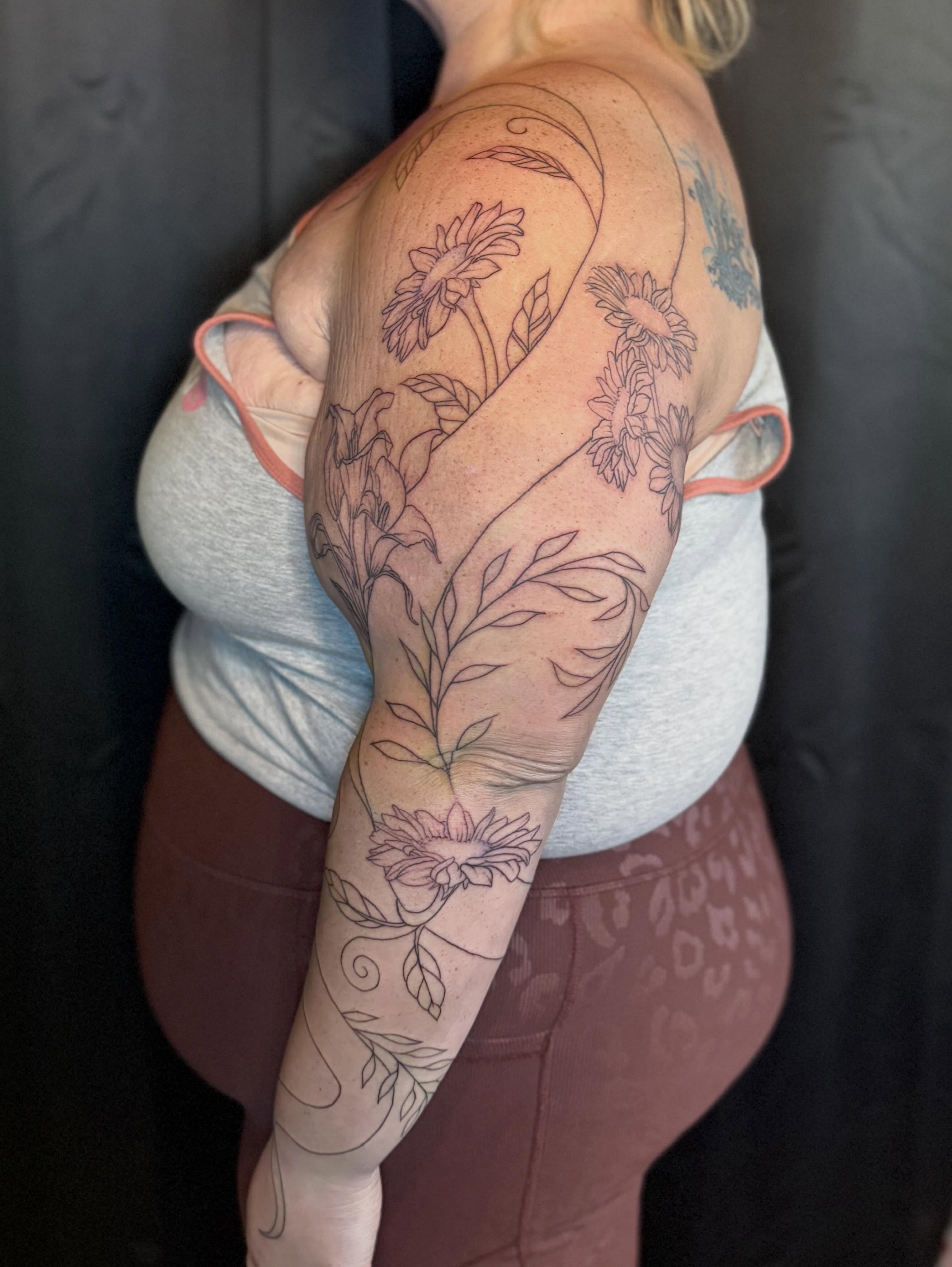 Floral design black and grey tattoo on the upper arm by Olivia, Royal Oak, Michigan