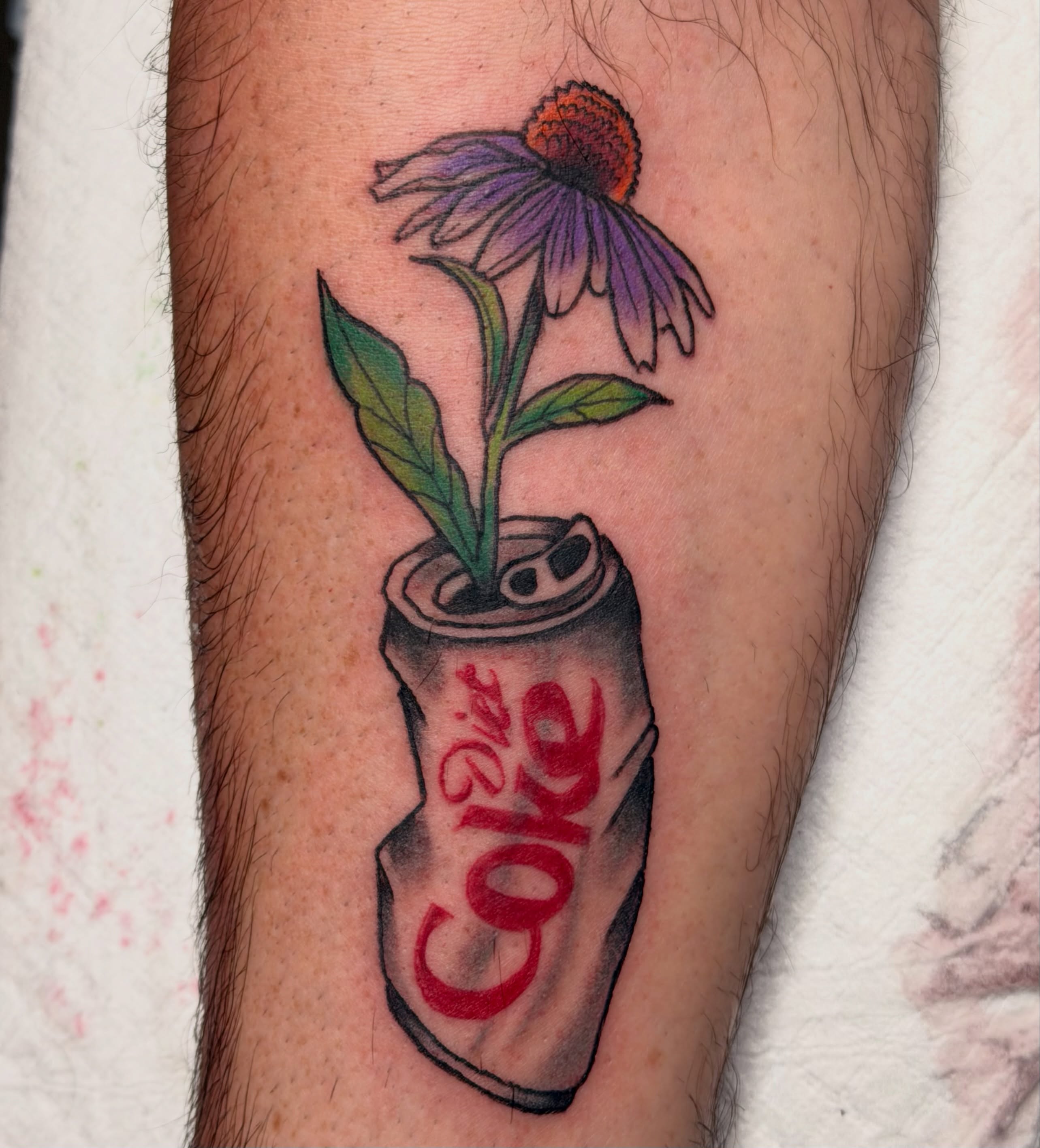 Purple flower in Diet Coke can realism tattoo on the forearm by Kelsey Turnis
