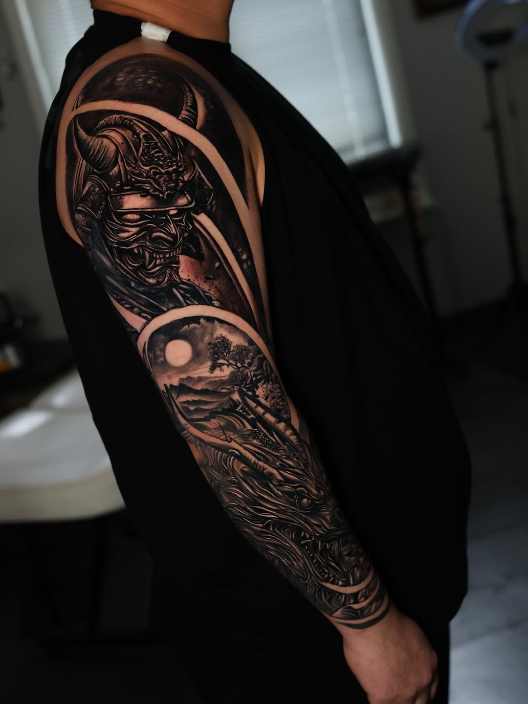 Samurai mask and dragon landscape Japanese tattoo on the upper arm by Insight Ink Tattoo