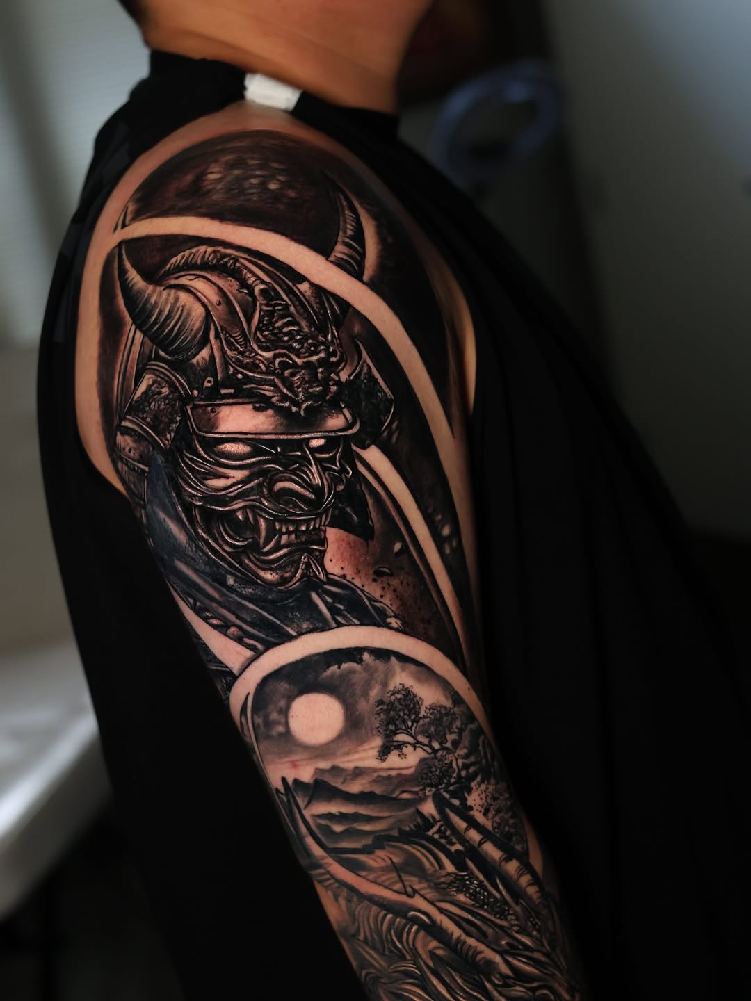 Samurai mask and landscape Japanese tattoo on the upper arm by Insight Ink Tattoo