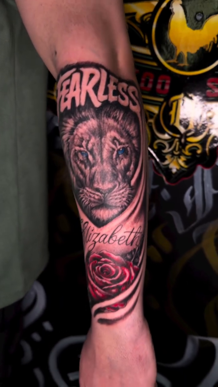 Lion and rose with text Chicano tattoo on the forearm by Oscar Saldaña