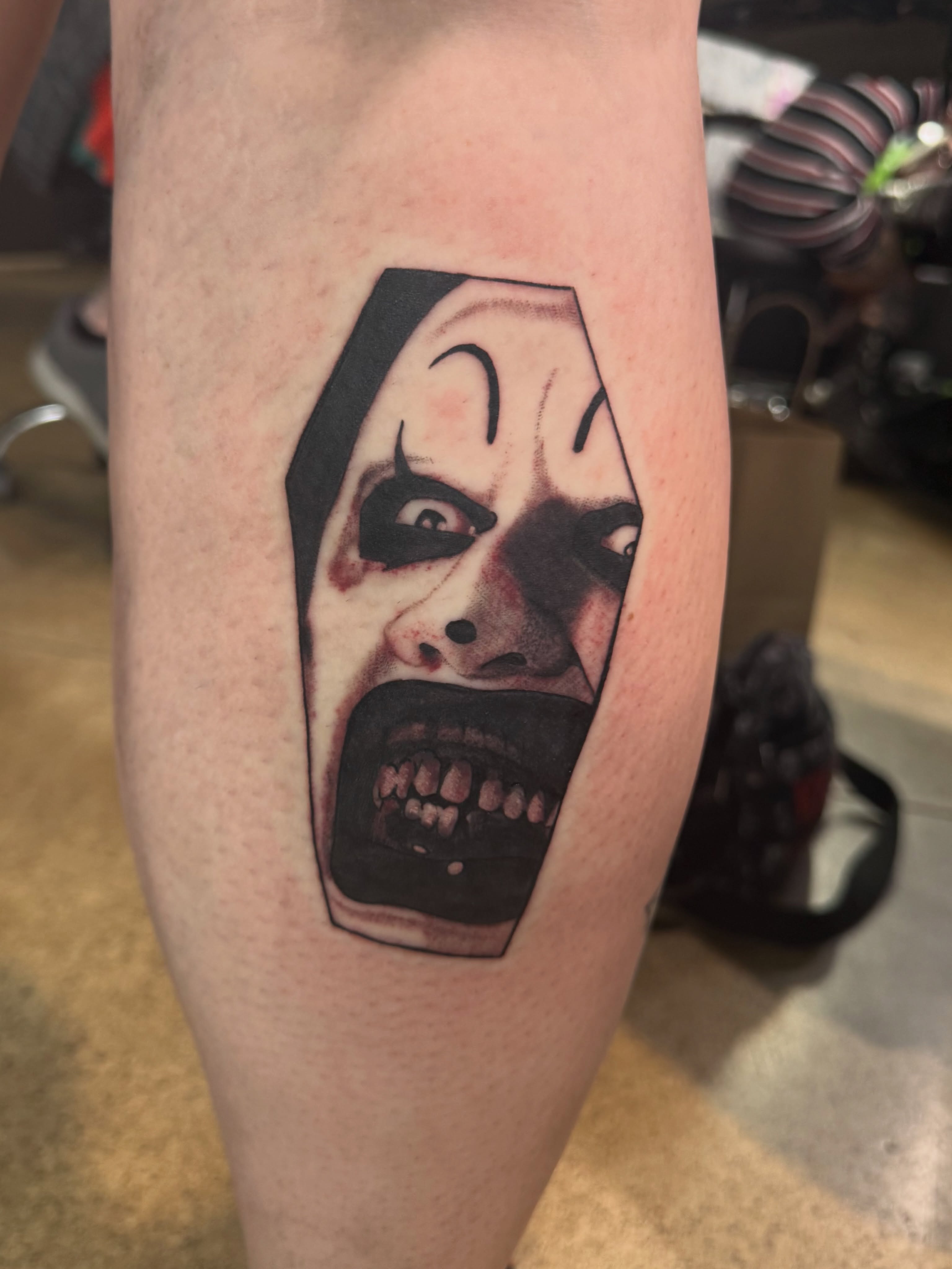 Clown face black and grey tattoo on the forearm by Mercy Dean