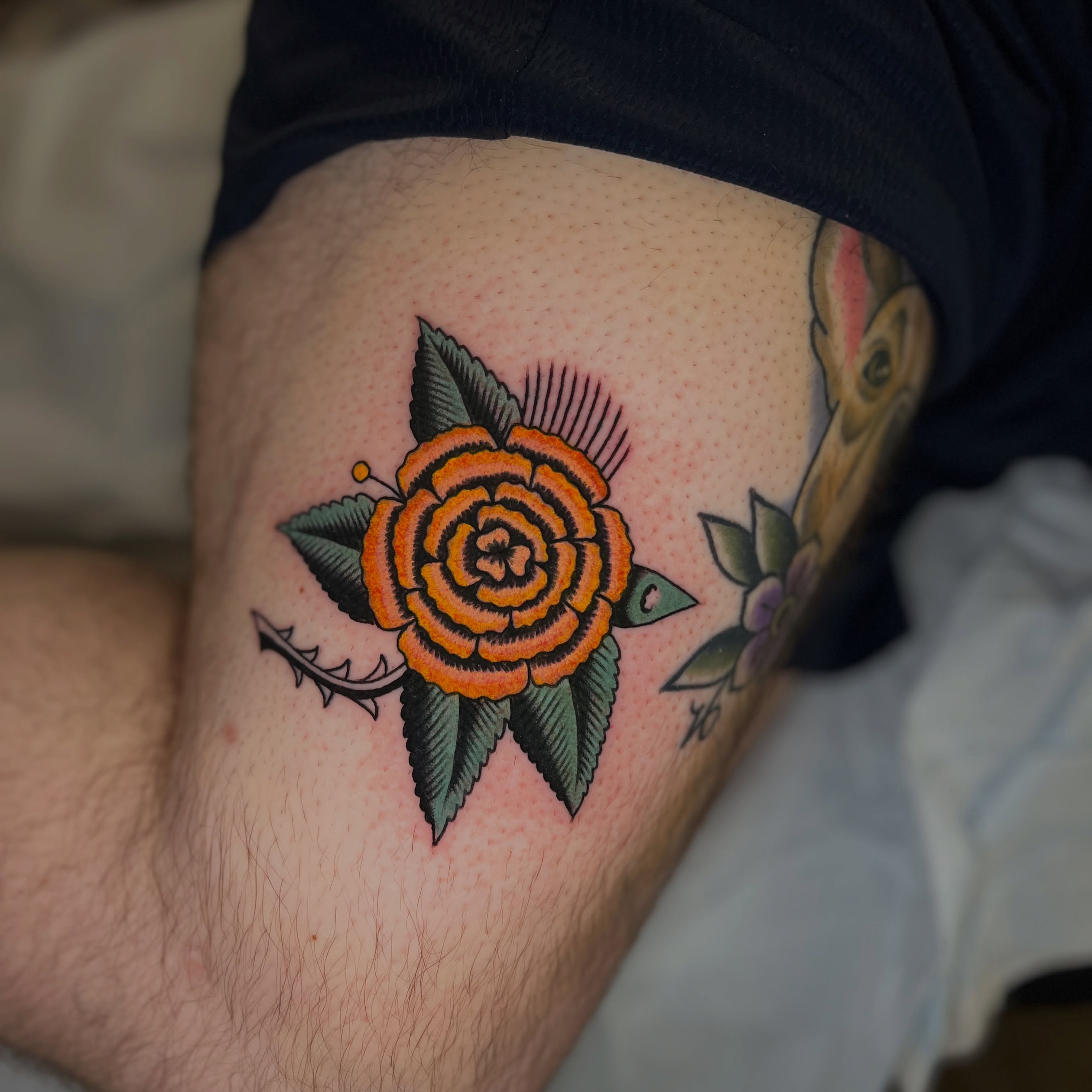 Orange rose American traditional tattoo on the thigh by Andrew Storm