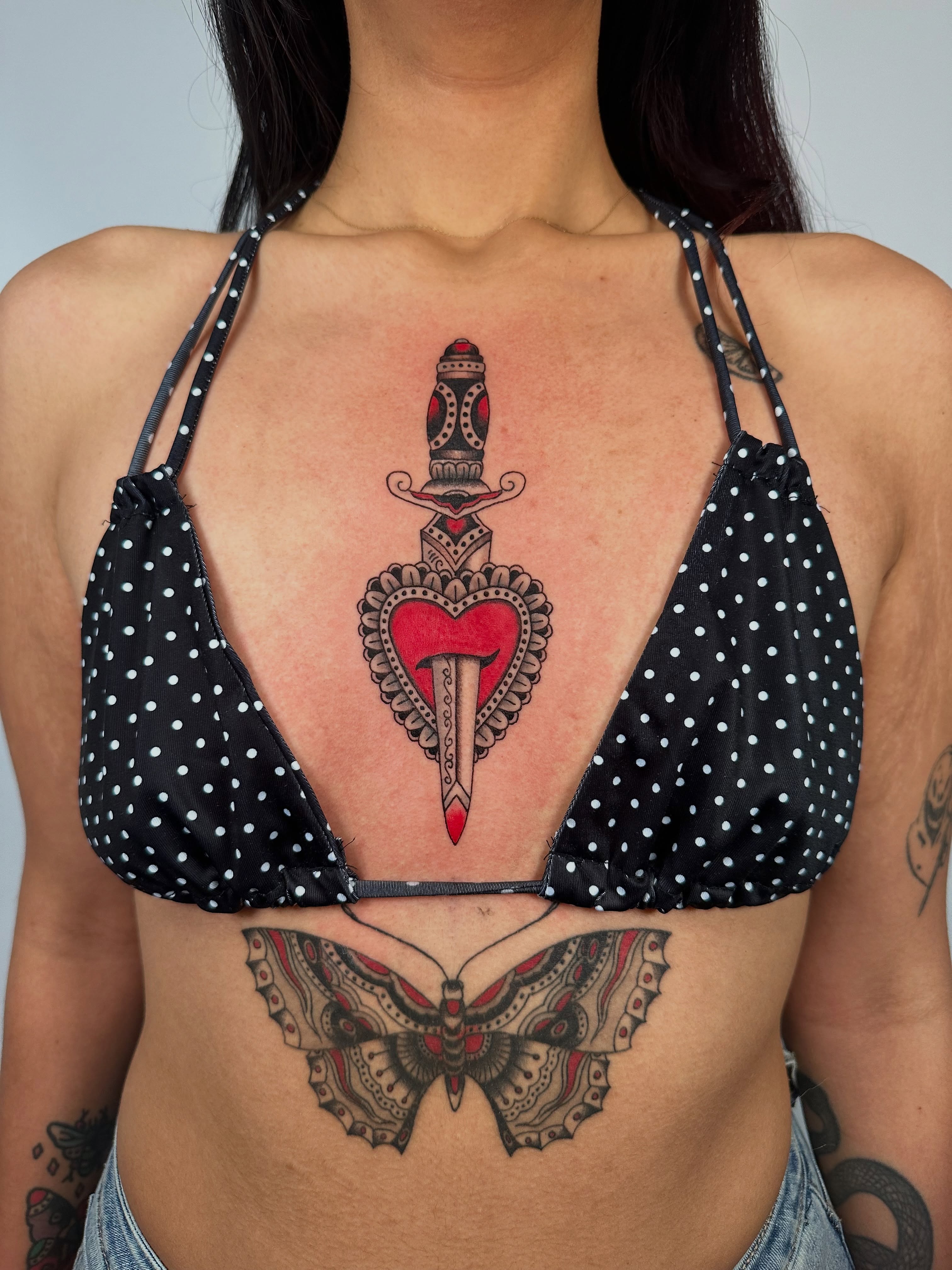 Heart with dagger American traditional tattoo on the chest by sechi