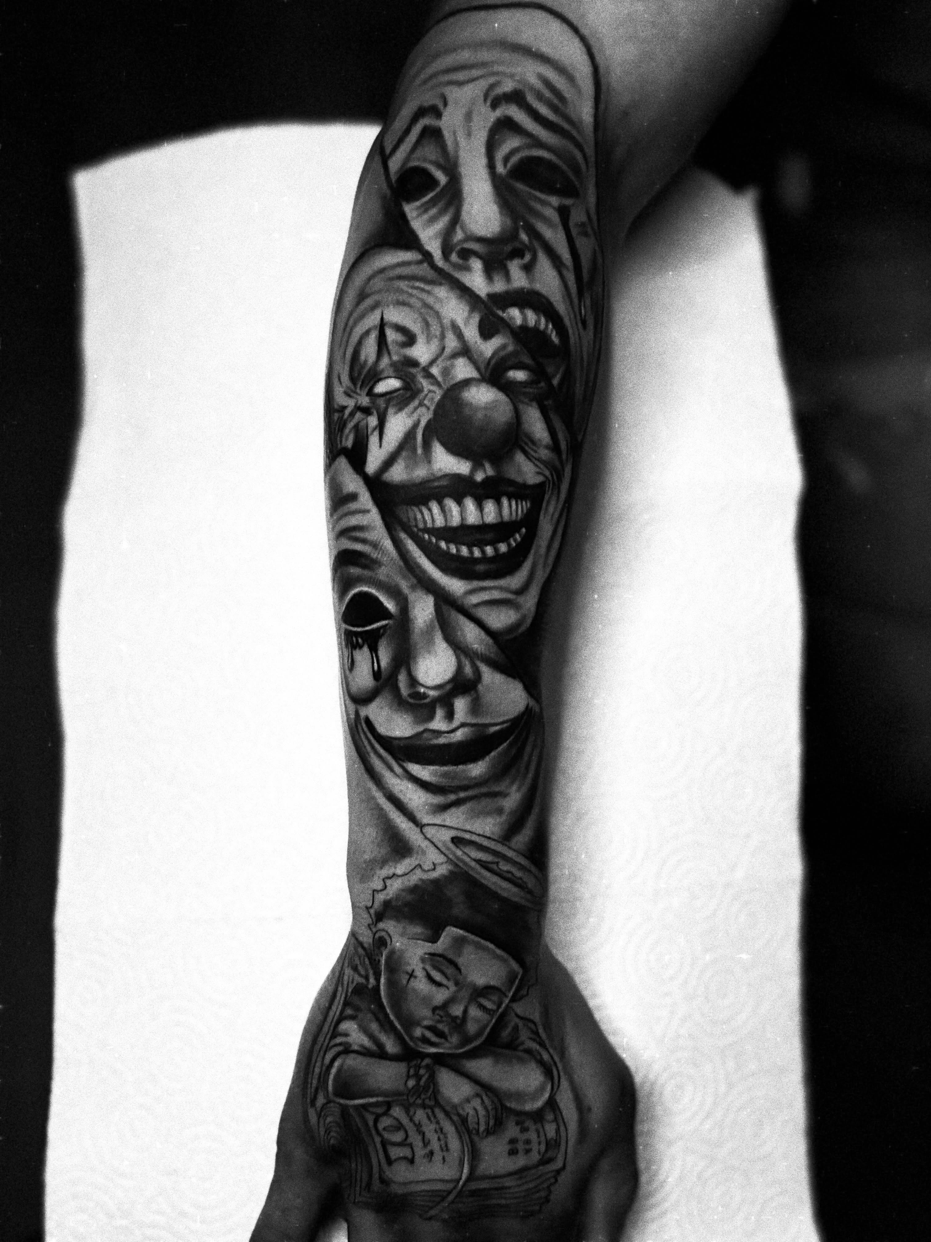 Clown faces black and grey tattoo on the forearm by Messias Tattoo Artist