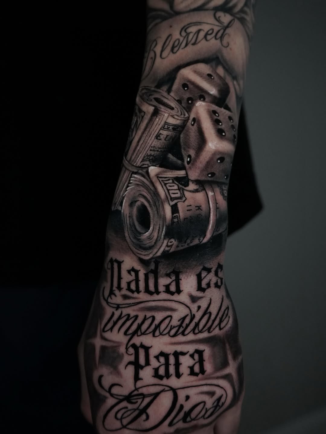 Money, dice, and script lettering Chicano tattoo on the forearm by Carlos Trujillo