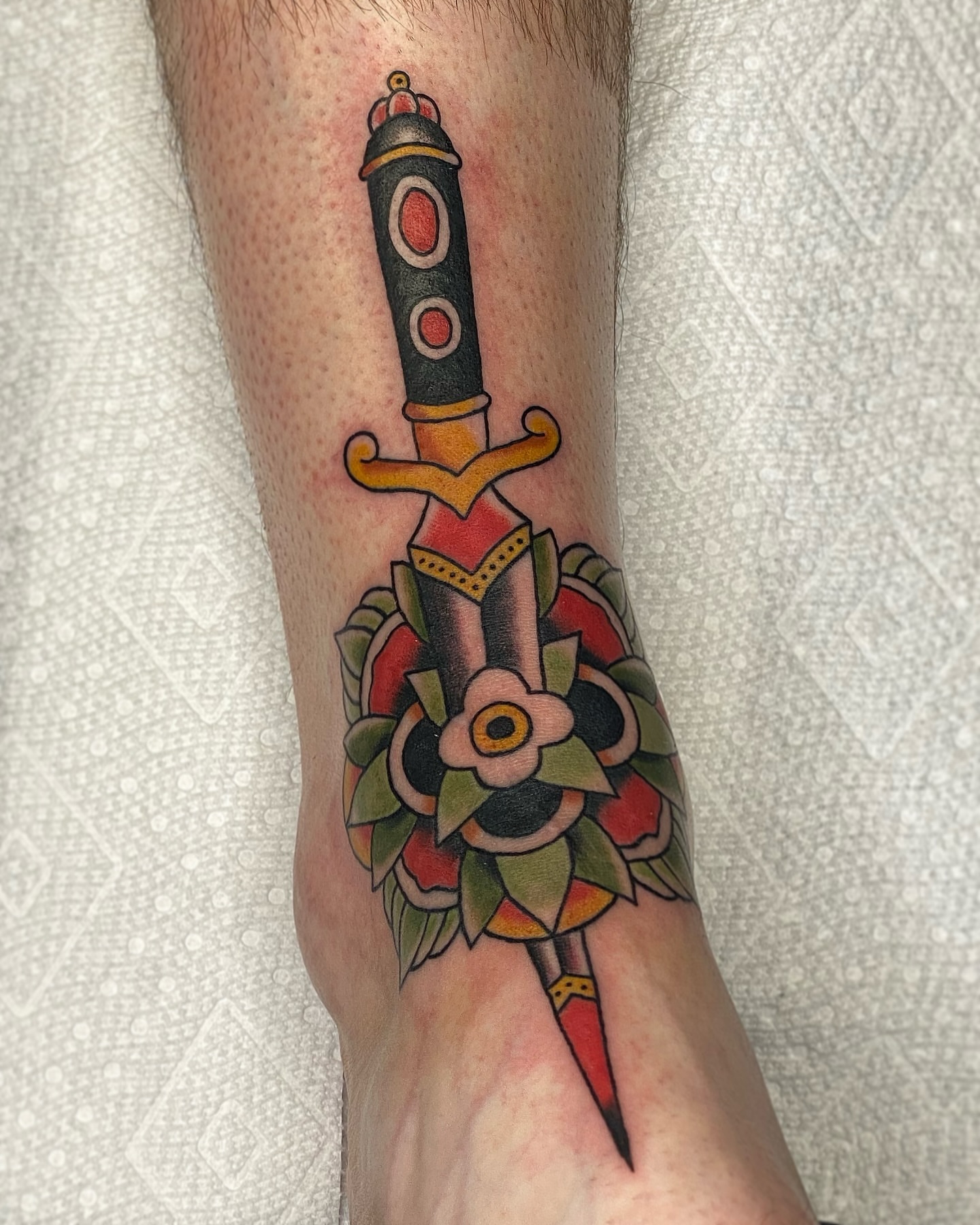 Sword and flower American traditional tattoo on the forearm by Corinne Carter