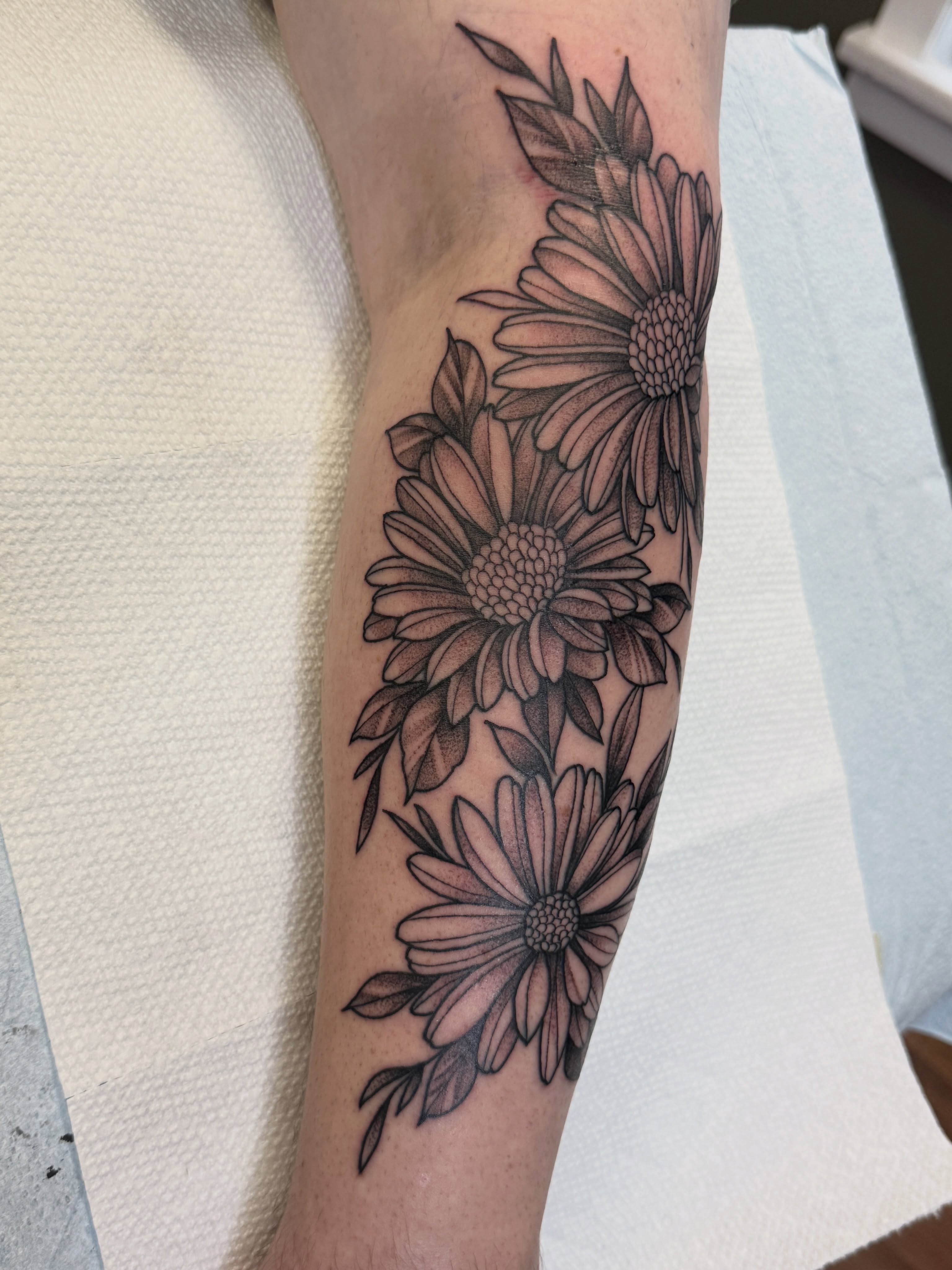 Daisies black and grey tattoo on the forearm by Jeremy Utley