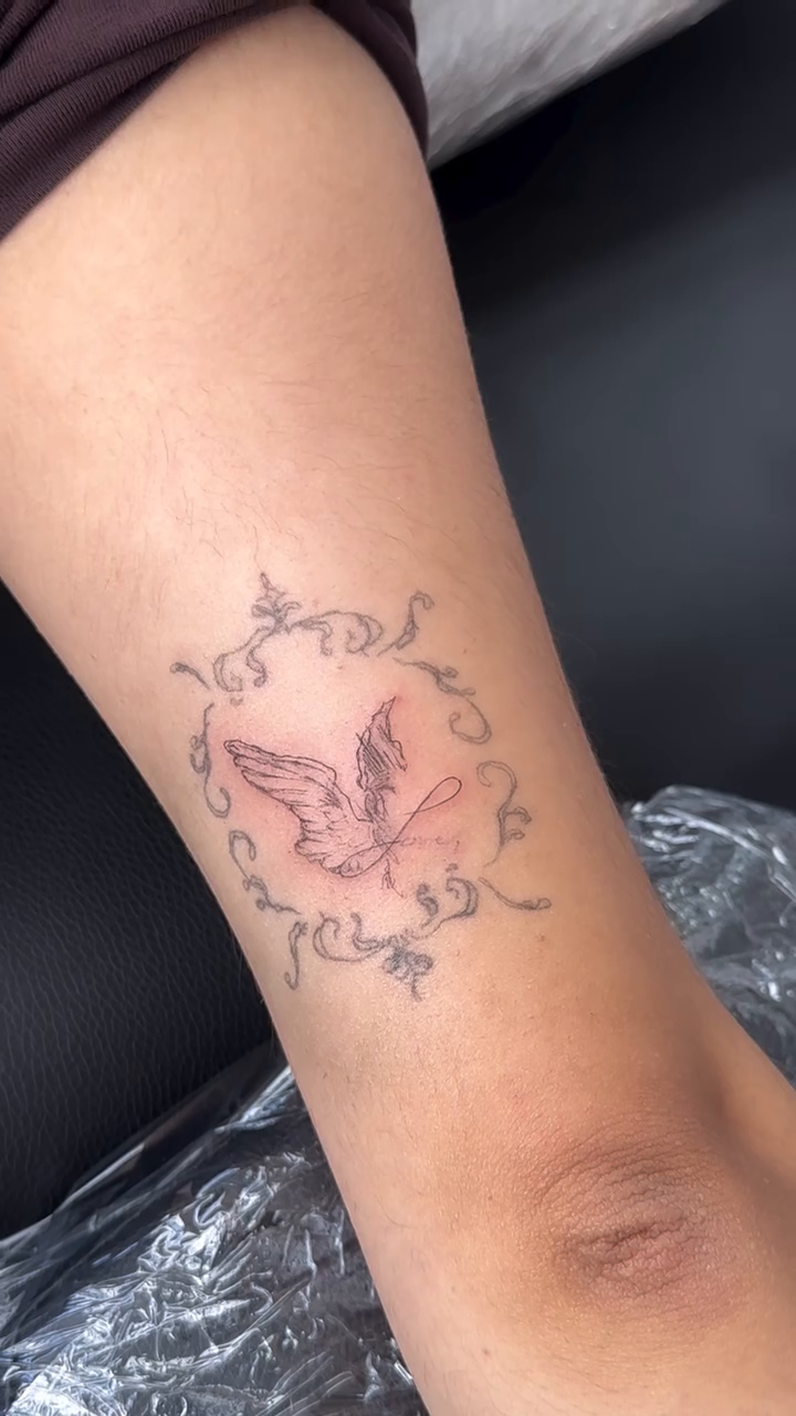 Butterfly within an ornamental frame fine line tattoo on the forearm by @taravychi