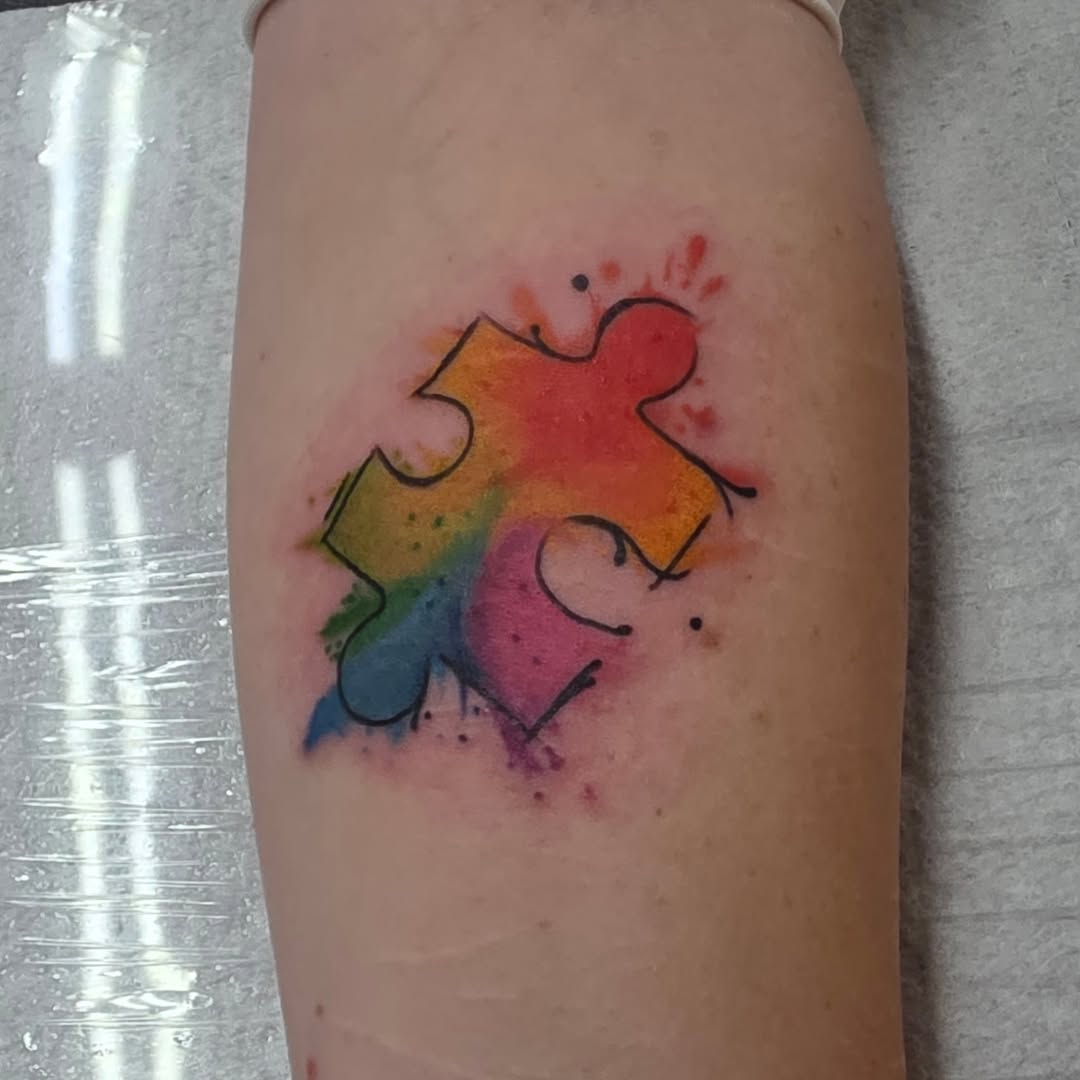 Jigsaw puzzle piece watercolor tattoo on the forearm by Moe