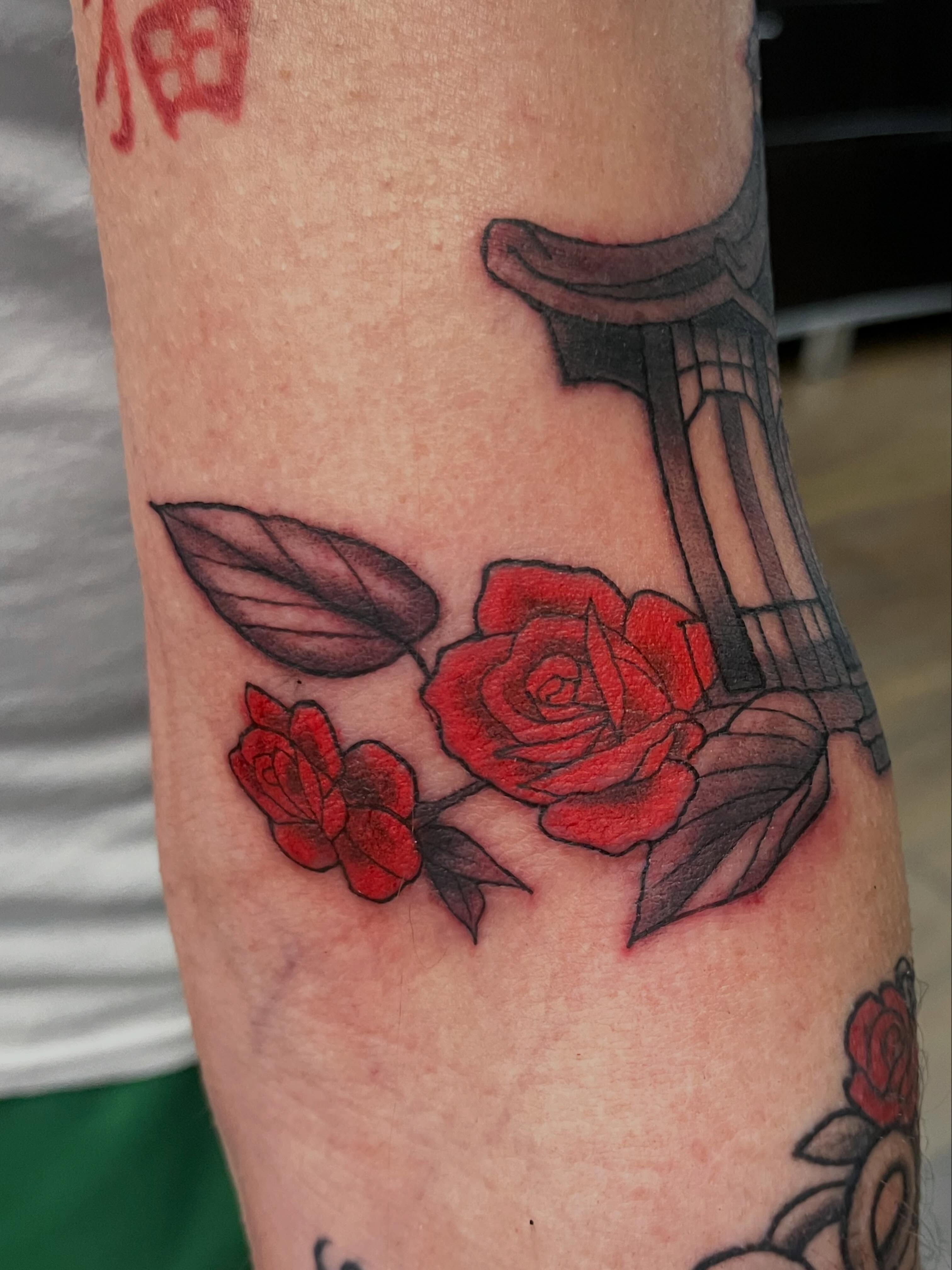 Red roses and column black and grey tattoo on the forearm by Brianna Jo Ballinghoff