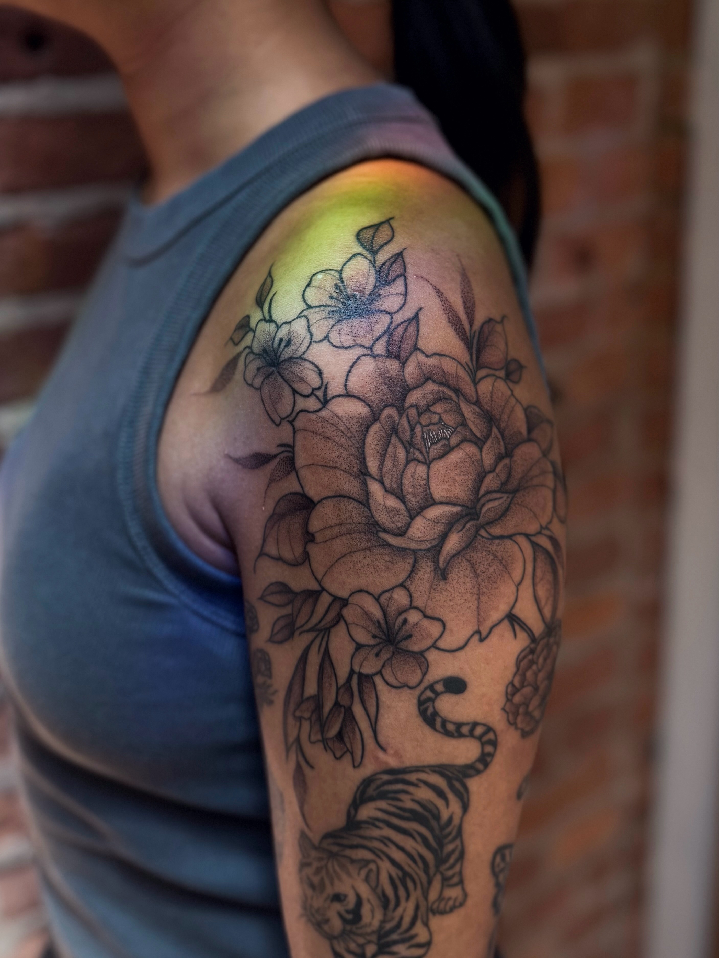 Floral tiger realism tattoo on the upper arm by Jessica Bloom