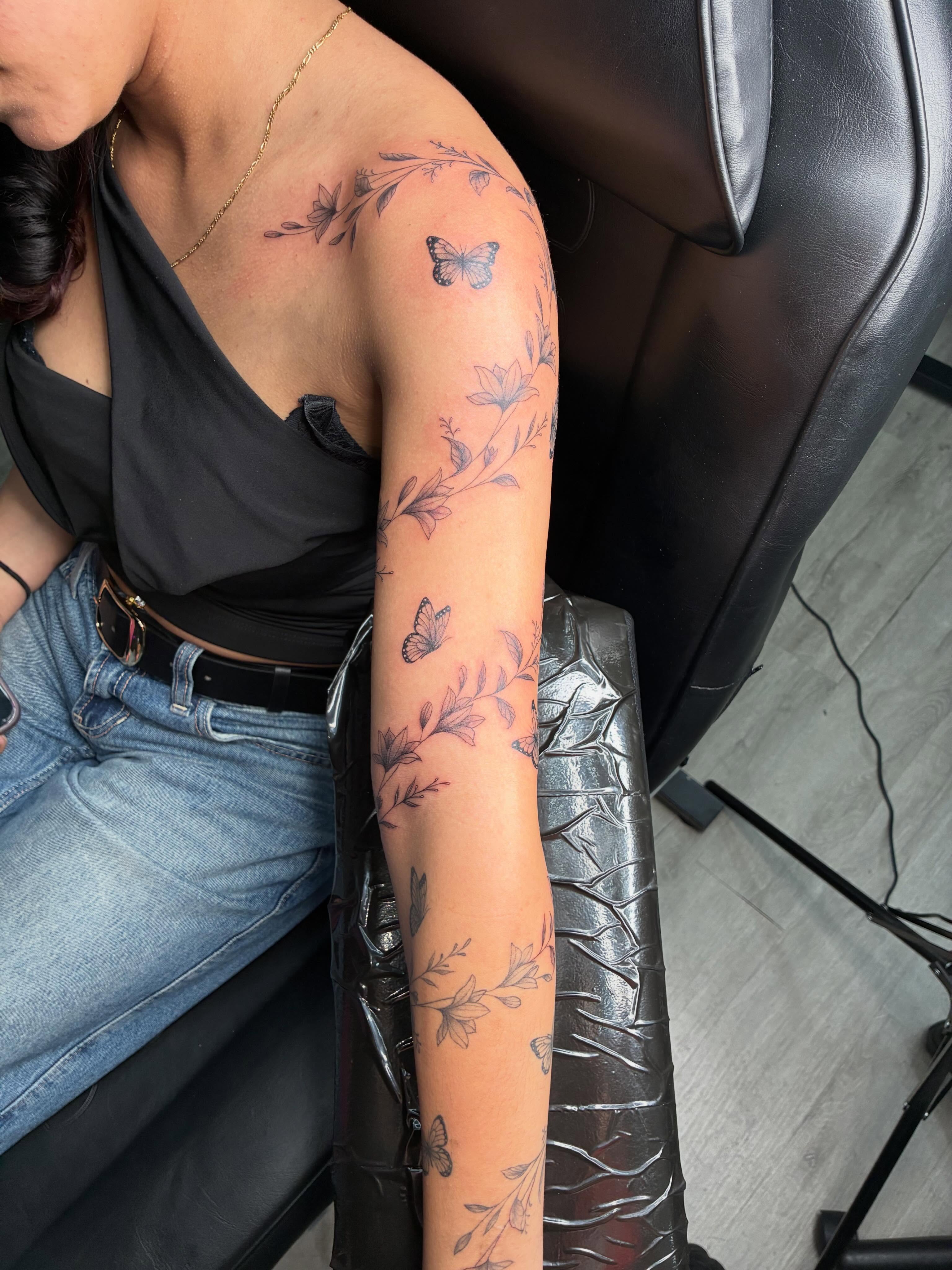 Butterflies and flowers fine line tattoo on the upper arm by Tattoos by Hailey