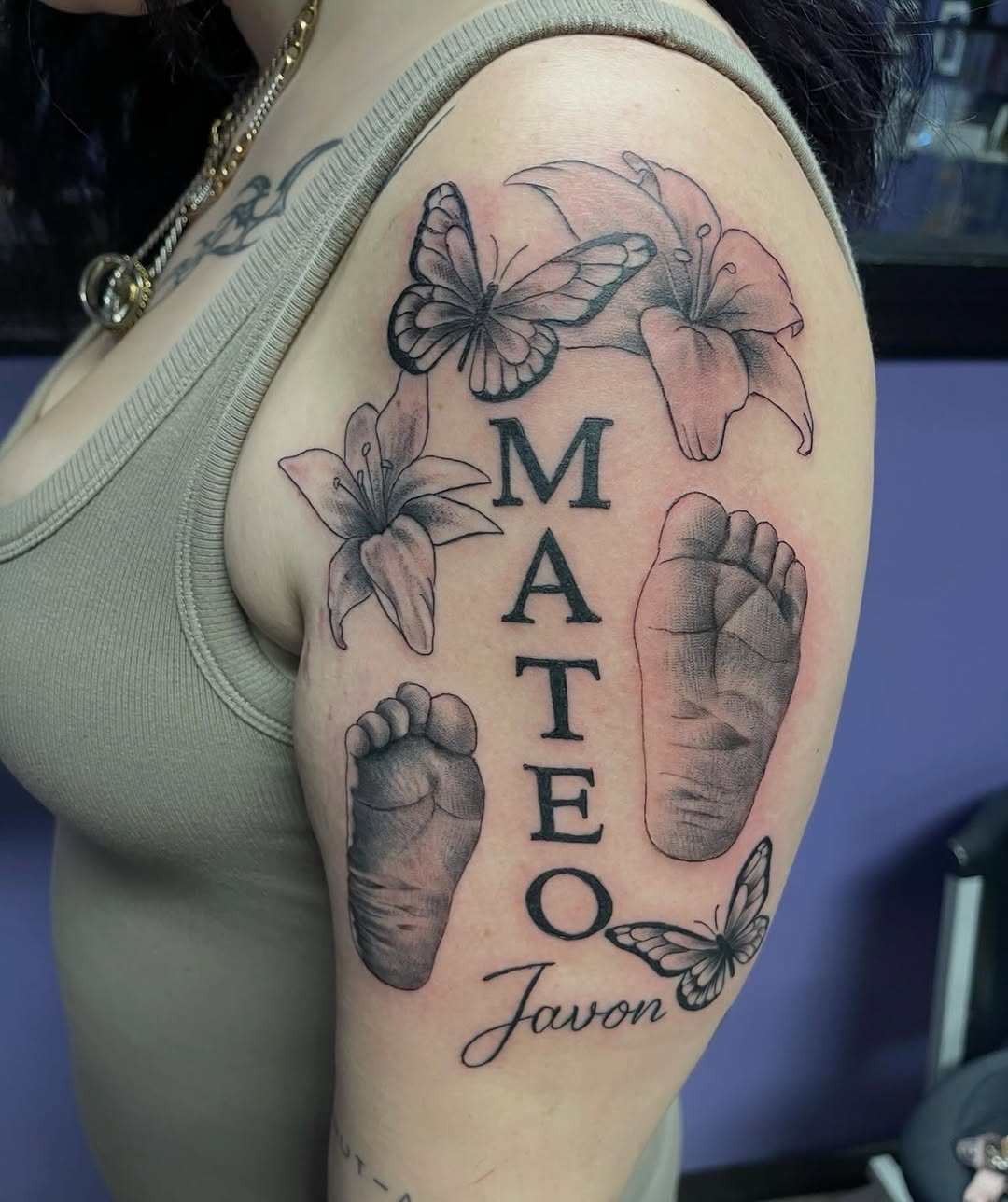 Baby footprints with name and flowers fine line tattoo on the shoulder by Mark Calloway