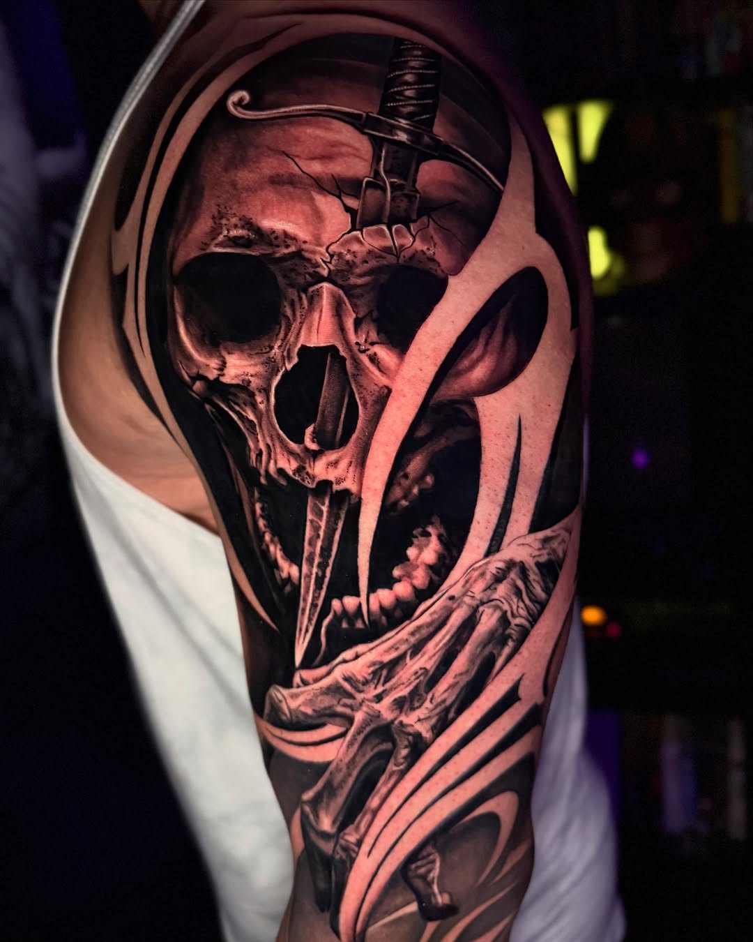 Skull with sword and skeleton hand realism tattoo on the forearm by Tommy Nguyen, Eastpointe, Michigan