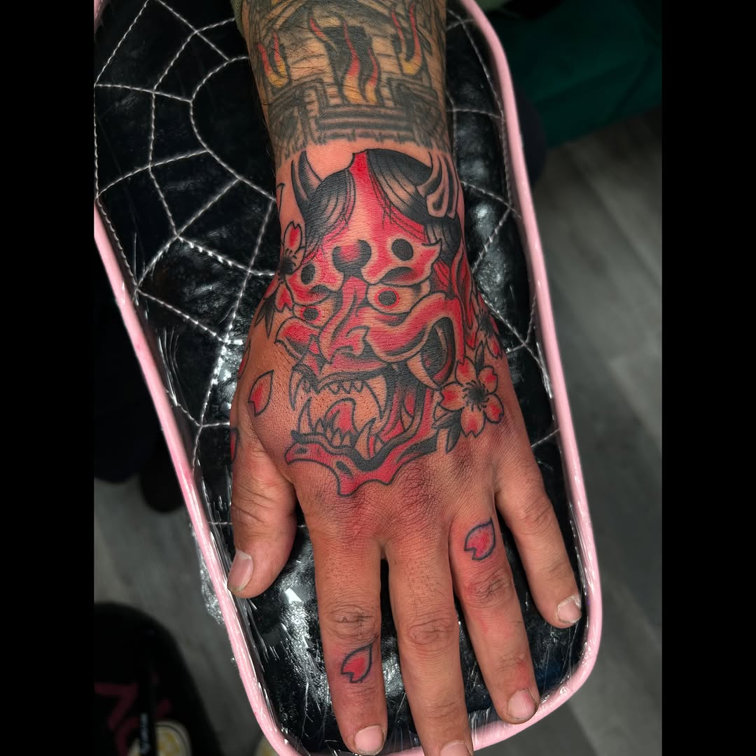 Demon mask American traditional tattoo on the hand by Audrey Migitsch