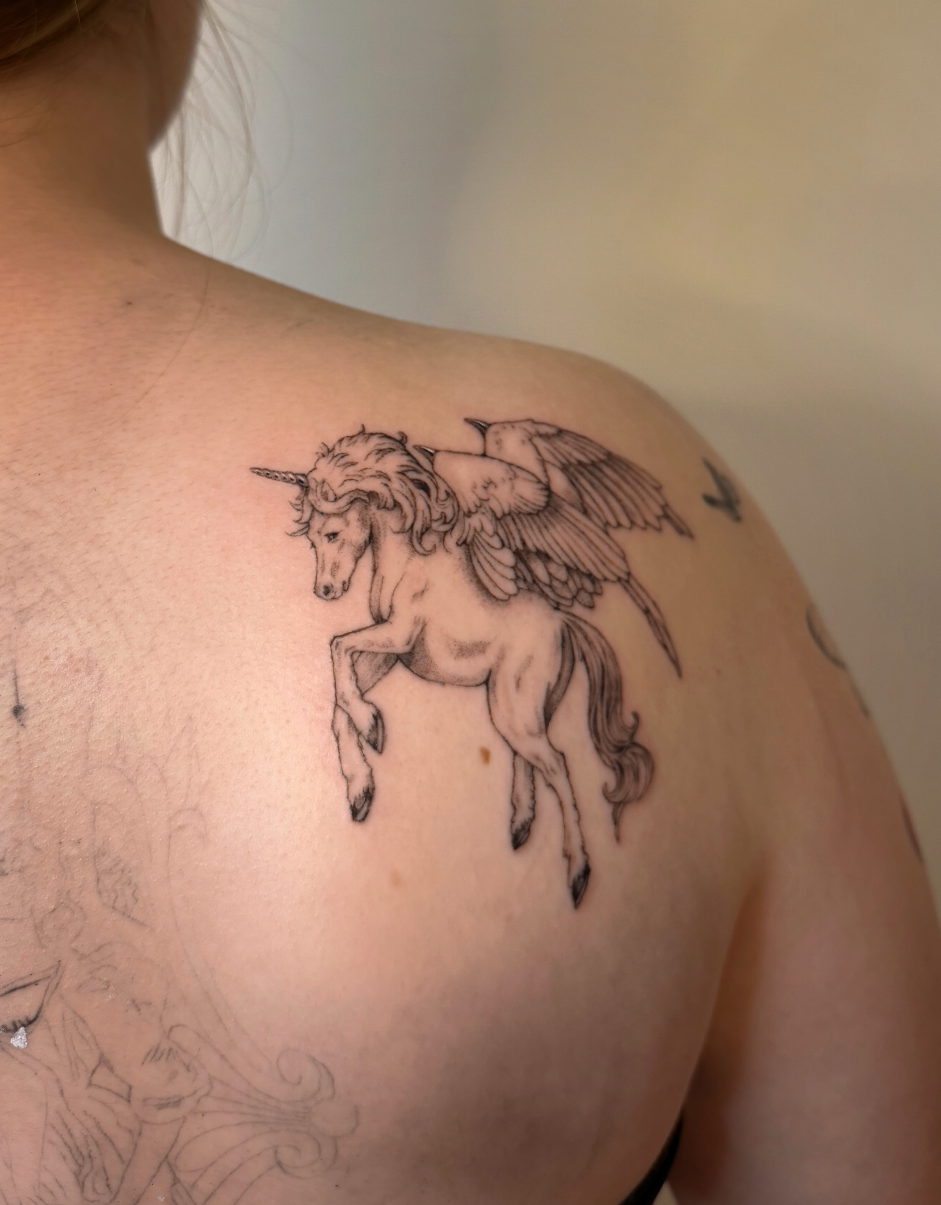 Unicorn with wings black and grey tattoo on the shoulder by Hery Anwar