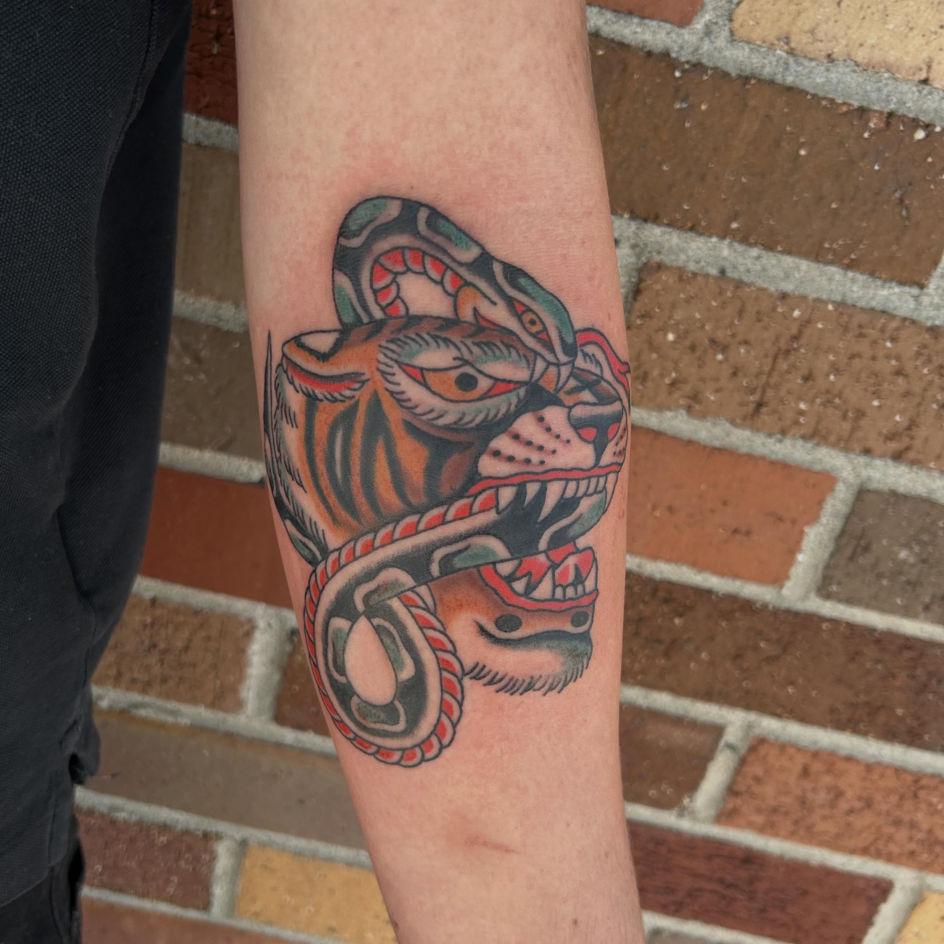 Tiger and snake American traditional tattoo on the forearm by Donny