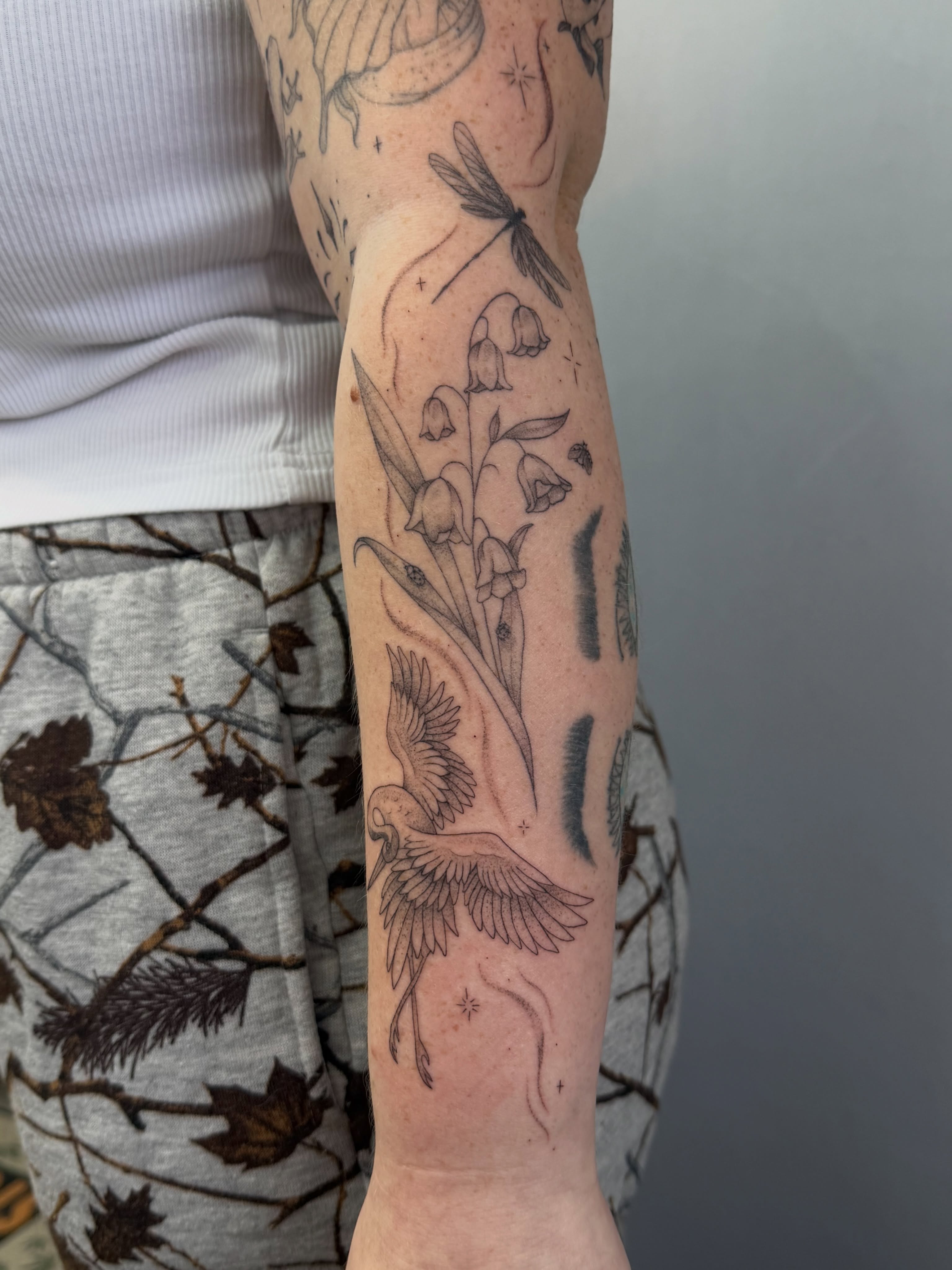 Bird and flowers black and grey tattoo on the forearm by Henesee Parfitt