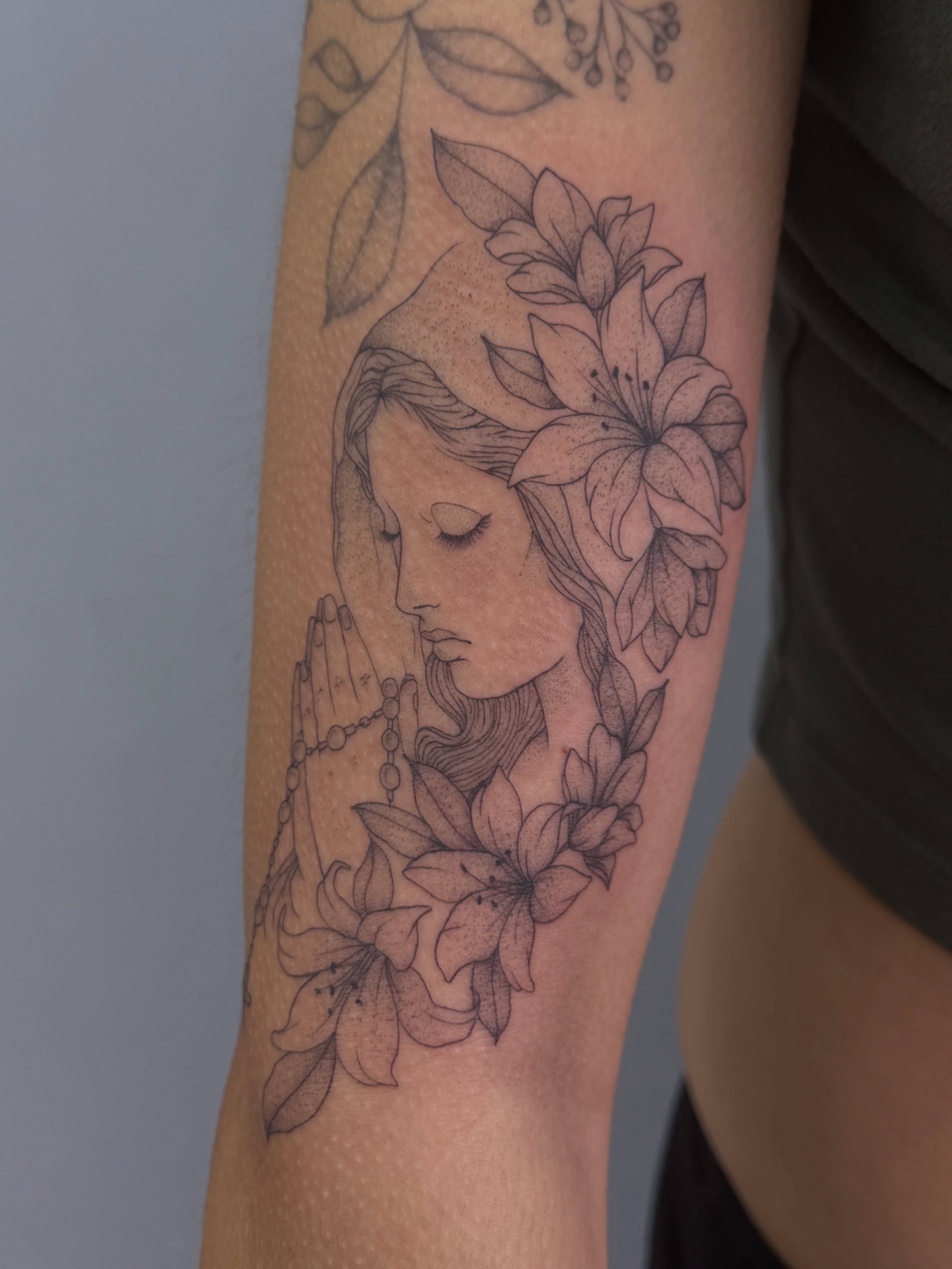 Praying woman with lilies dotwork tattoo on the forearm by Henesee Parfitt