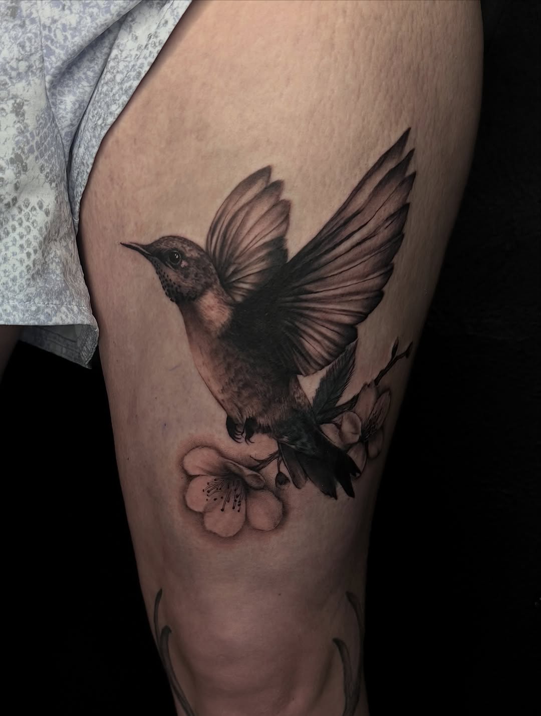 Hummingbird and flowers fine line tattoo on the thigh by Alexa Camacho
