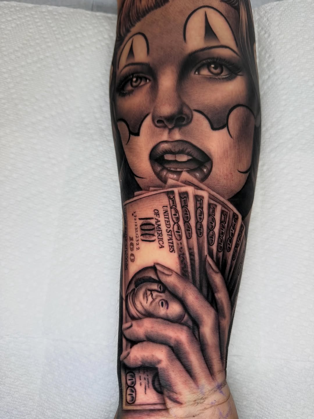 Woman with clown makeup and money Chicano tattoo on the forearm by LOS