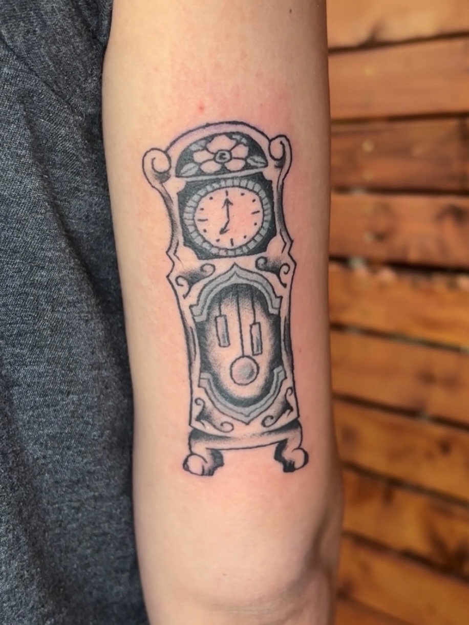 Grandfather clock black and grey tattoo on the forearm by Lilly Evans