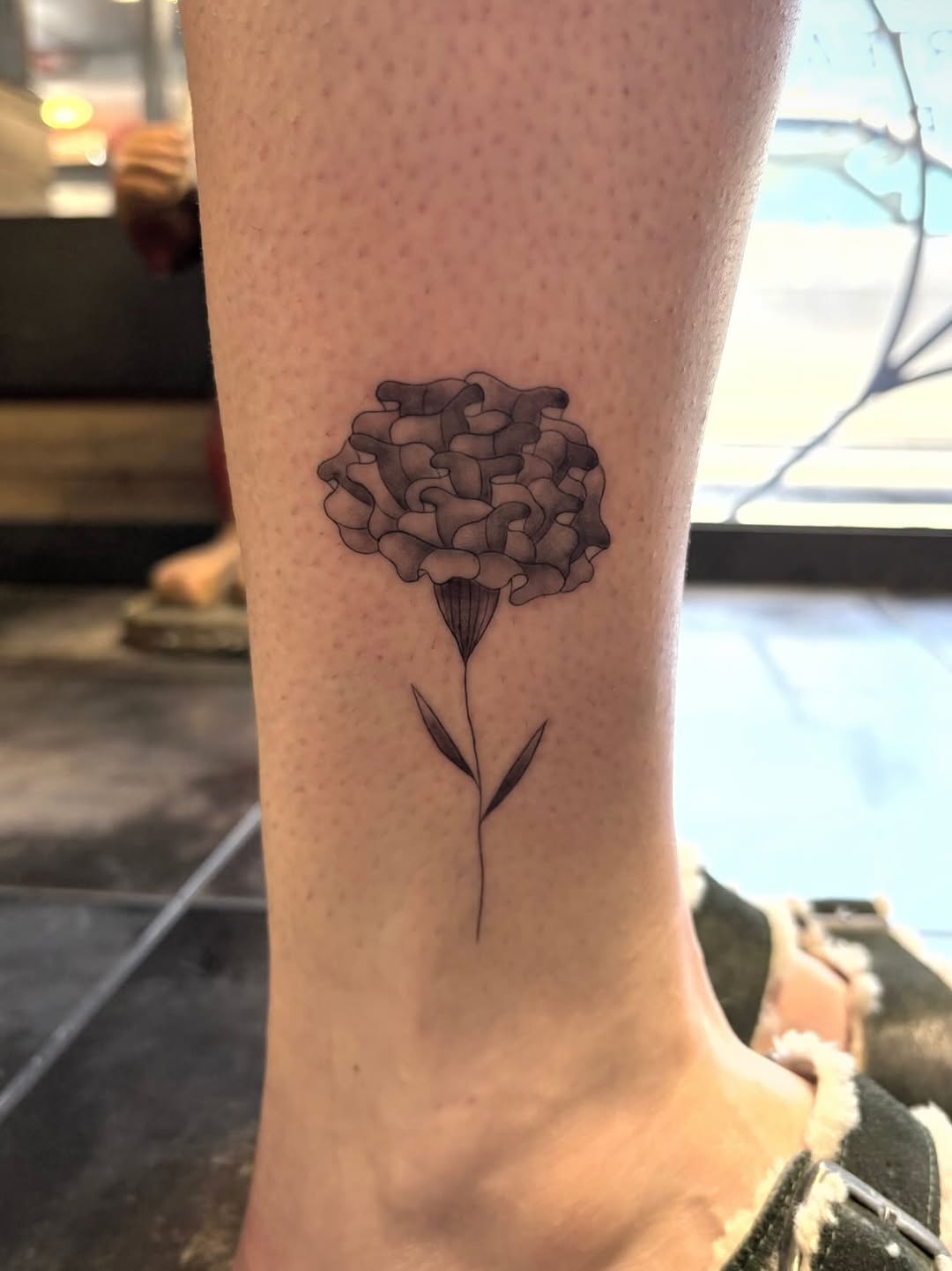 Marigold flower dotwork tattoo on the forearm by alana khounmeuang