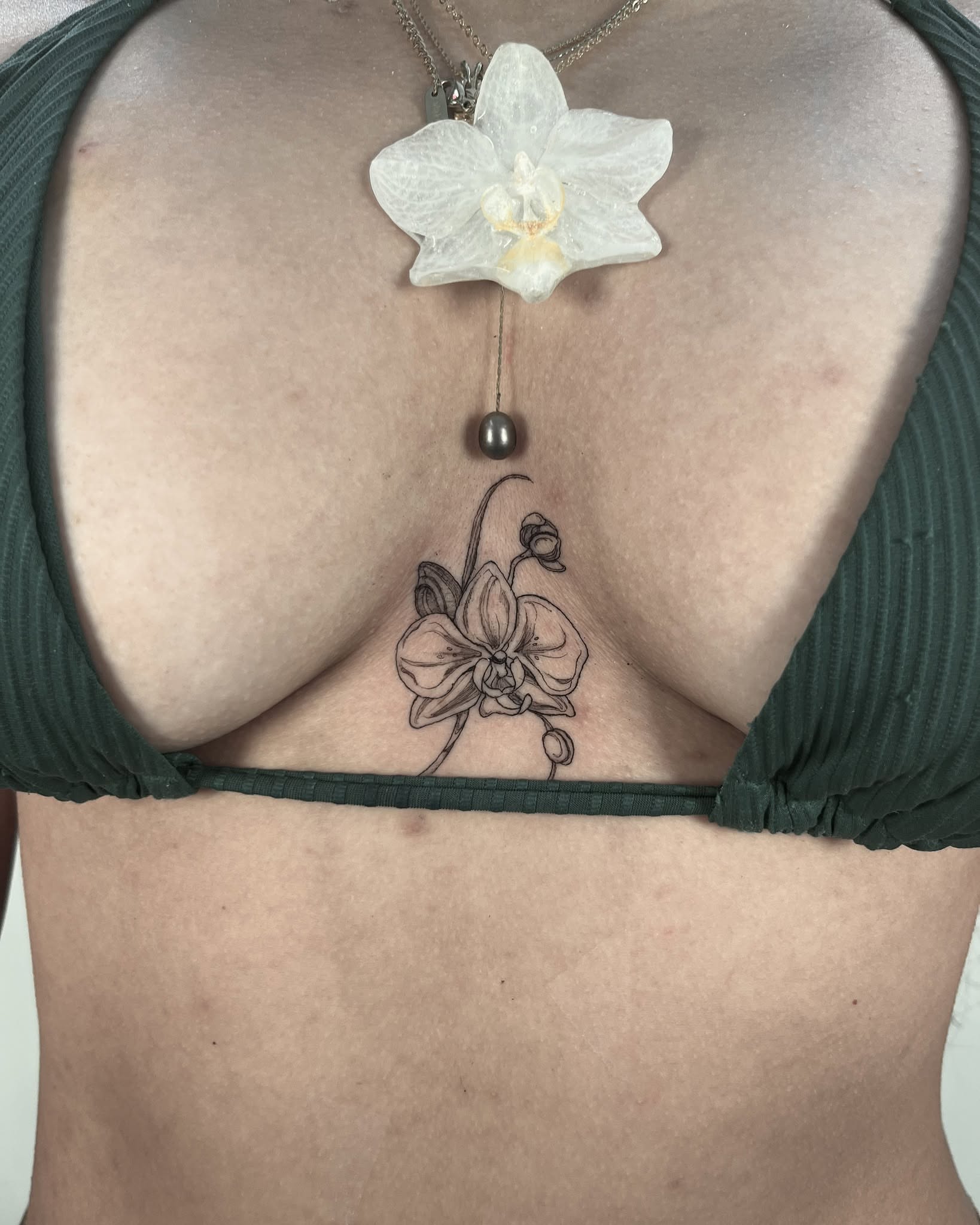 Orchid black and grey tattoo on the chest by Sierra Skye