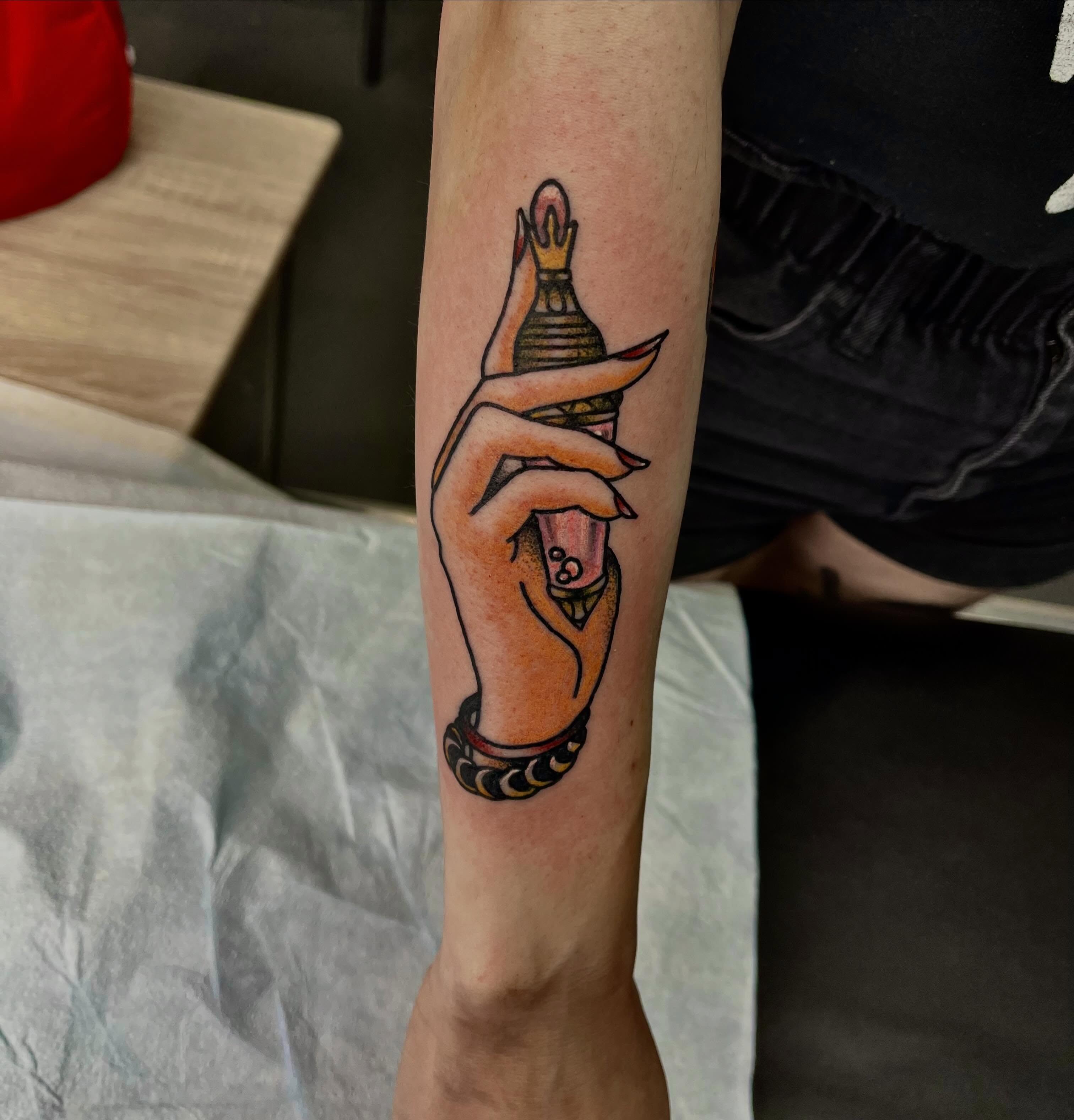 Hand holding crown American traditional tattoo on the forearm by Mason McCubbin