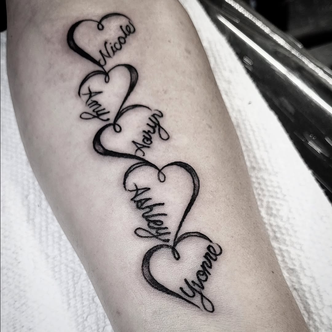 Heart-shaped names lettering script tattoo on the forearm by S. Madrid