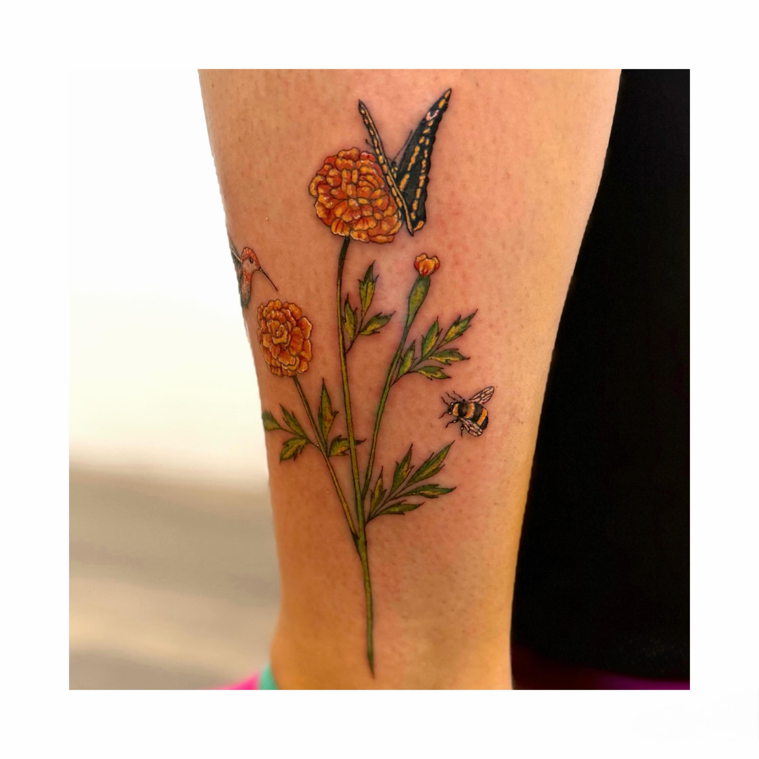 Marigold and bee realism tattoo on the forearm by Jessica Abbey
