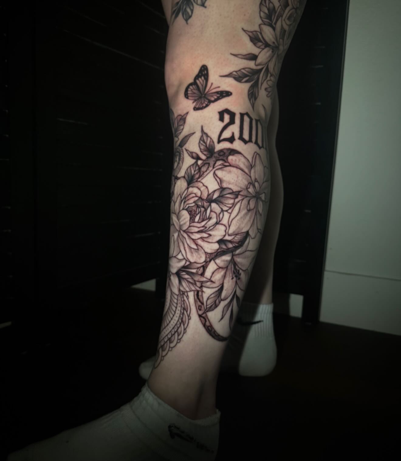 Floral and butterfly black and grey tattoo on the forearm by Sad Girl Tattoos