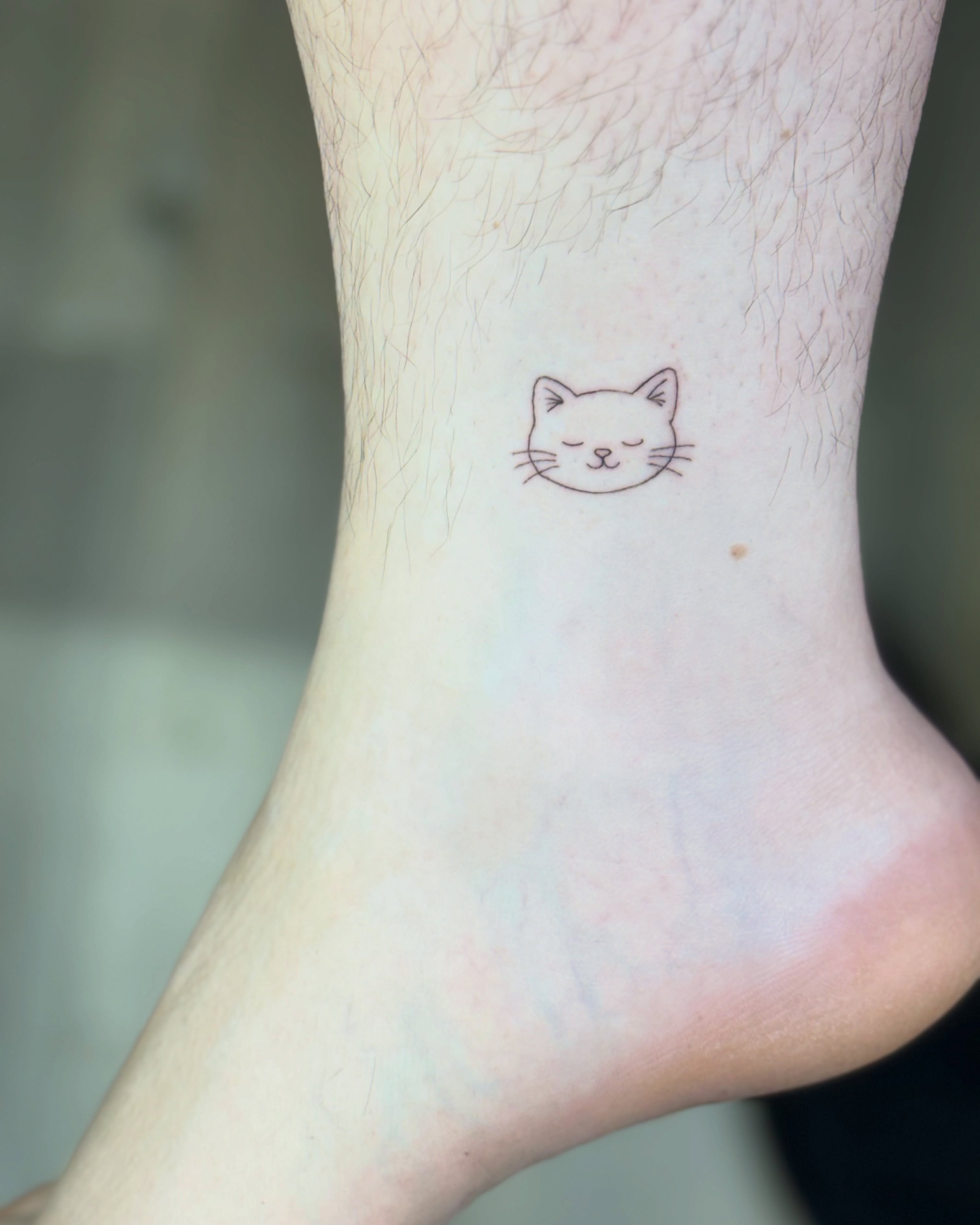 Cat face minimalist tattoo on the foot by Fineline Tattoo