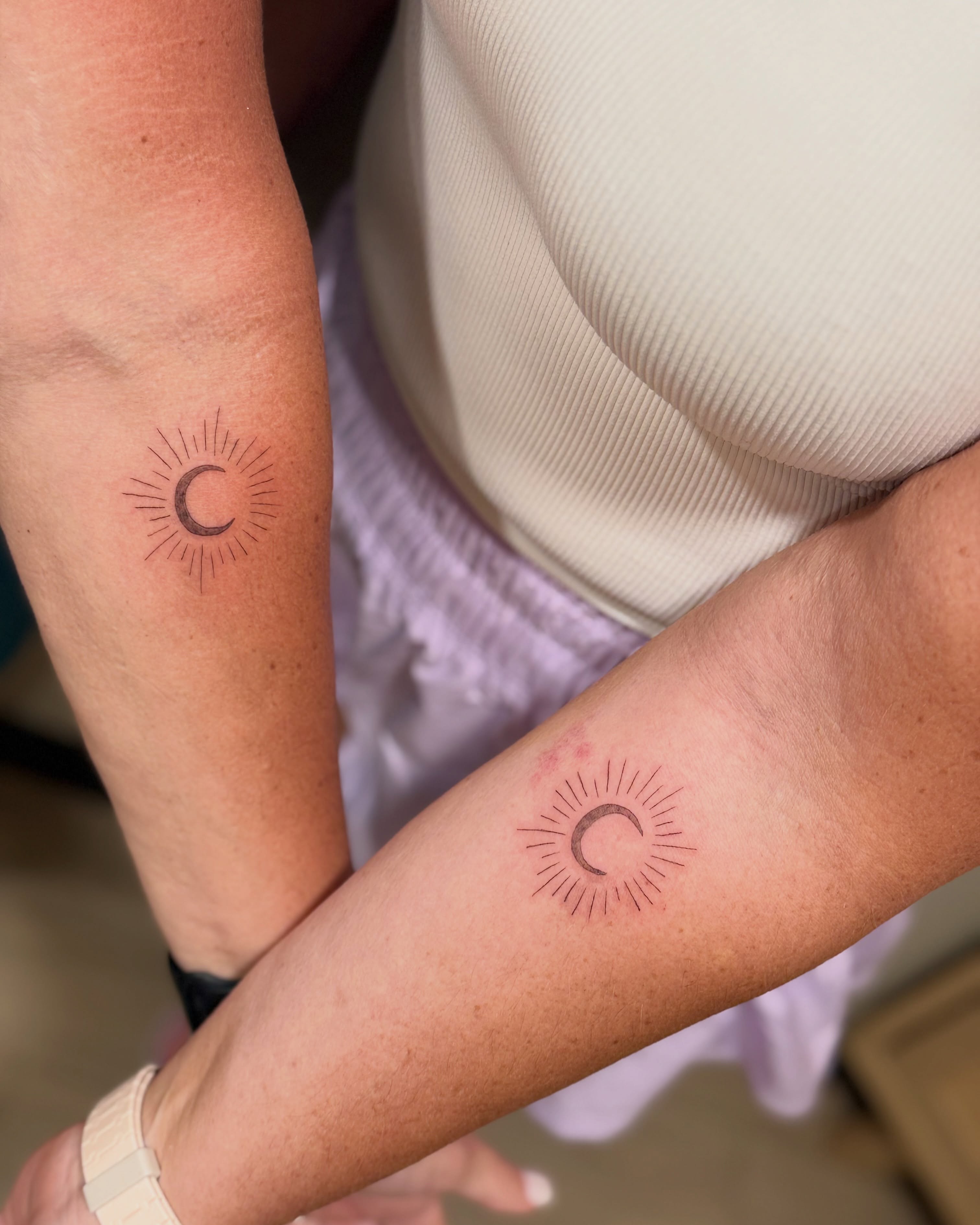 Sun and crescent moon minimalist tattoo on the forearm by Fineline Tattoo