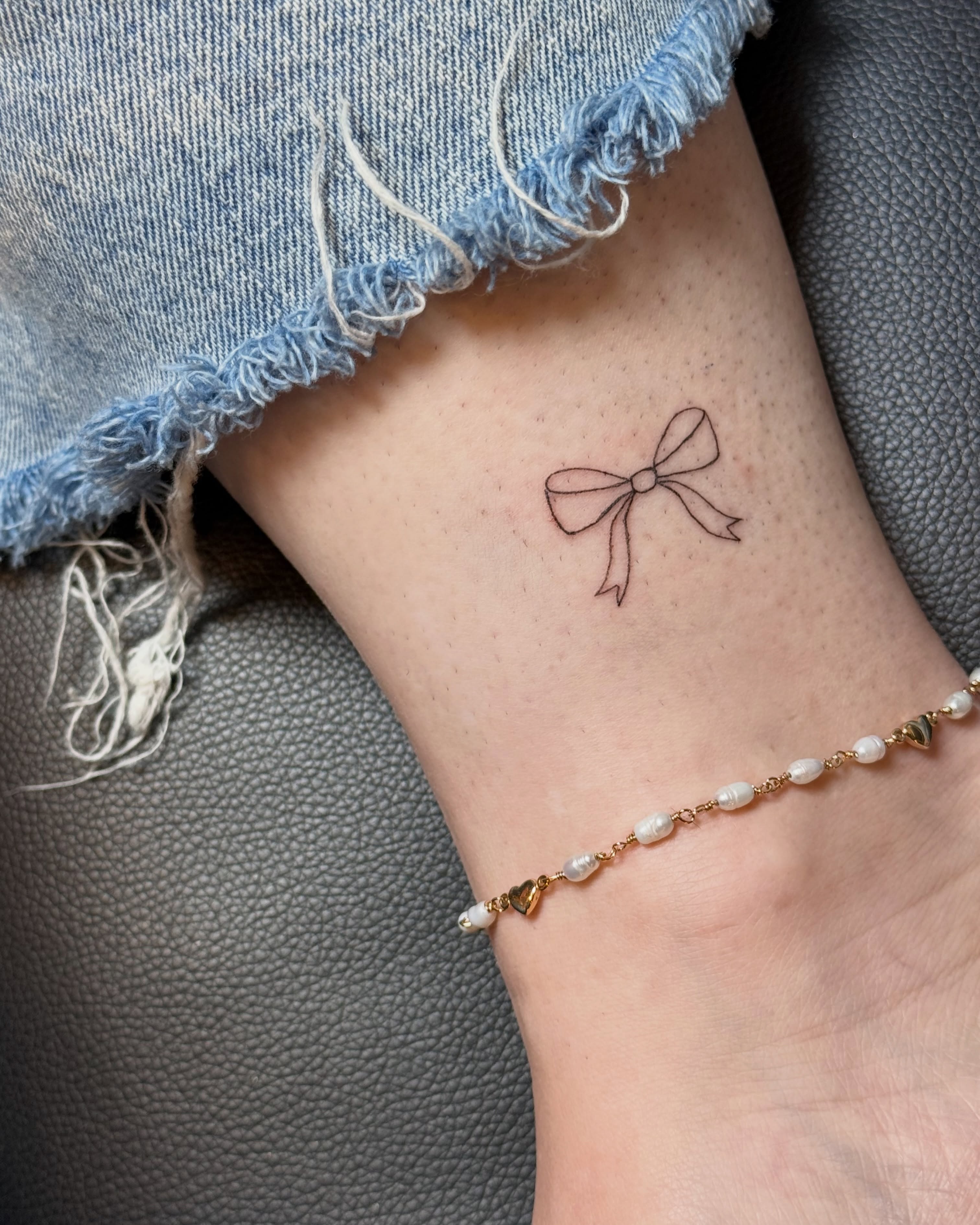 Bow fine line tattoo on the forearm by Fineline Tattoo