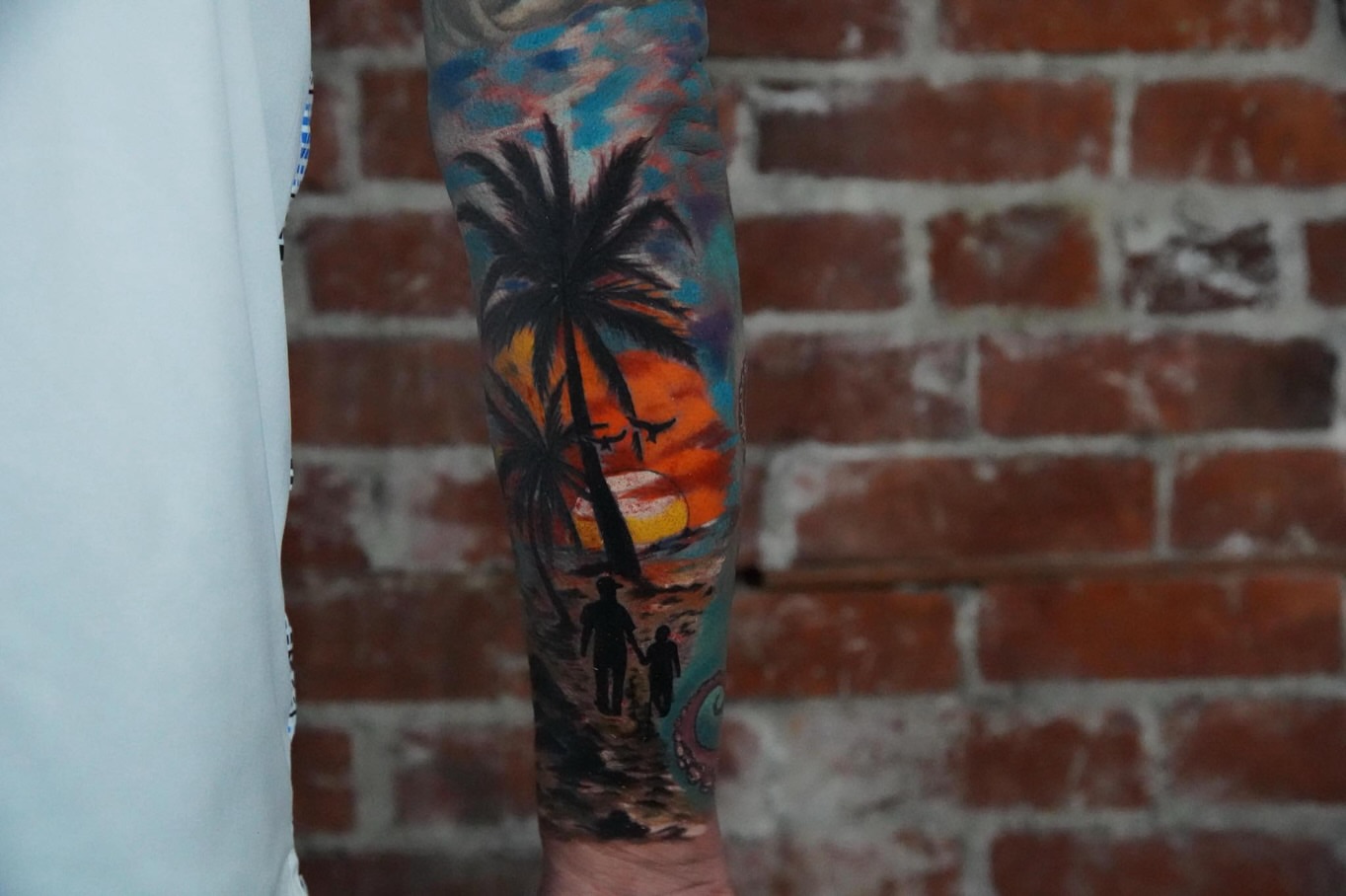 Sunset beach scene watercolor tattoo on the forearm by Elijah Tattoos, San Diego, California