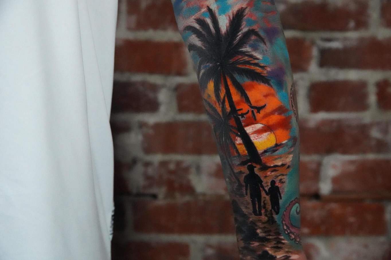 Sunset beach scene watercolor tattoo on the forearm by Elijah Tattoos, San Diego, California