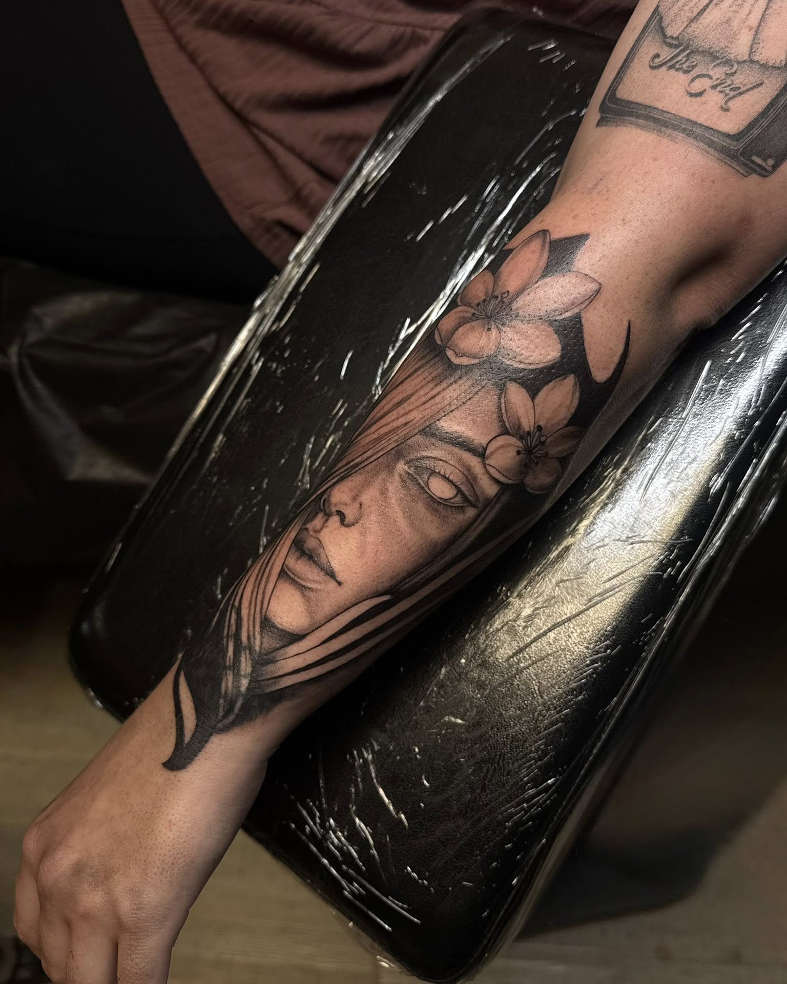 Woman's face with flowers realism tattoo on the forearm by Madison Jasso