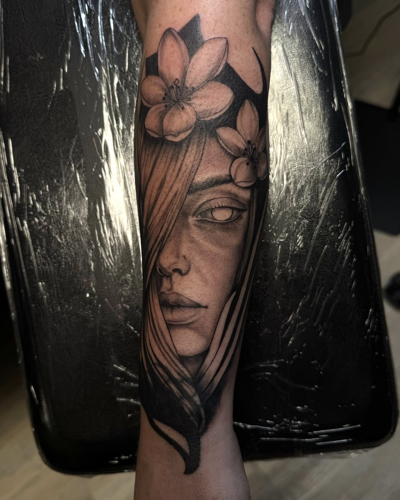 Woman's face with flowers realism tattoo on the forearm by Madison Jasso